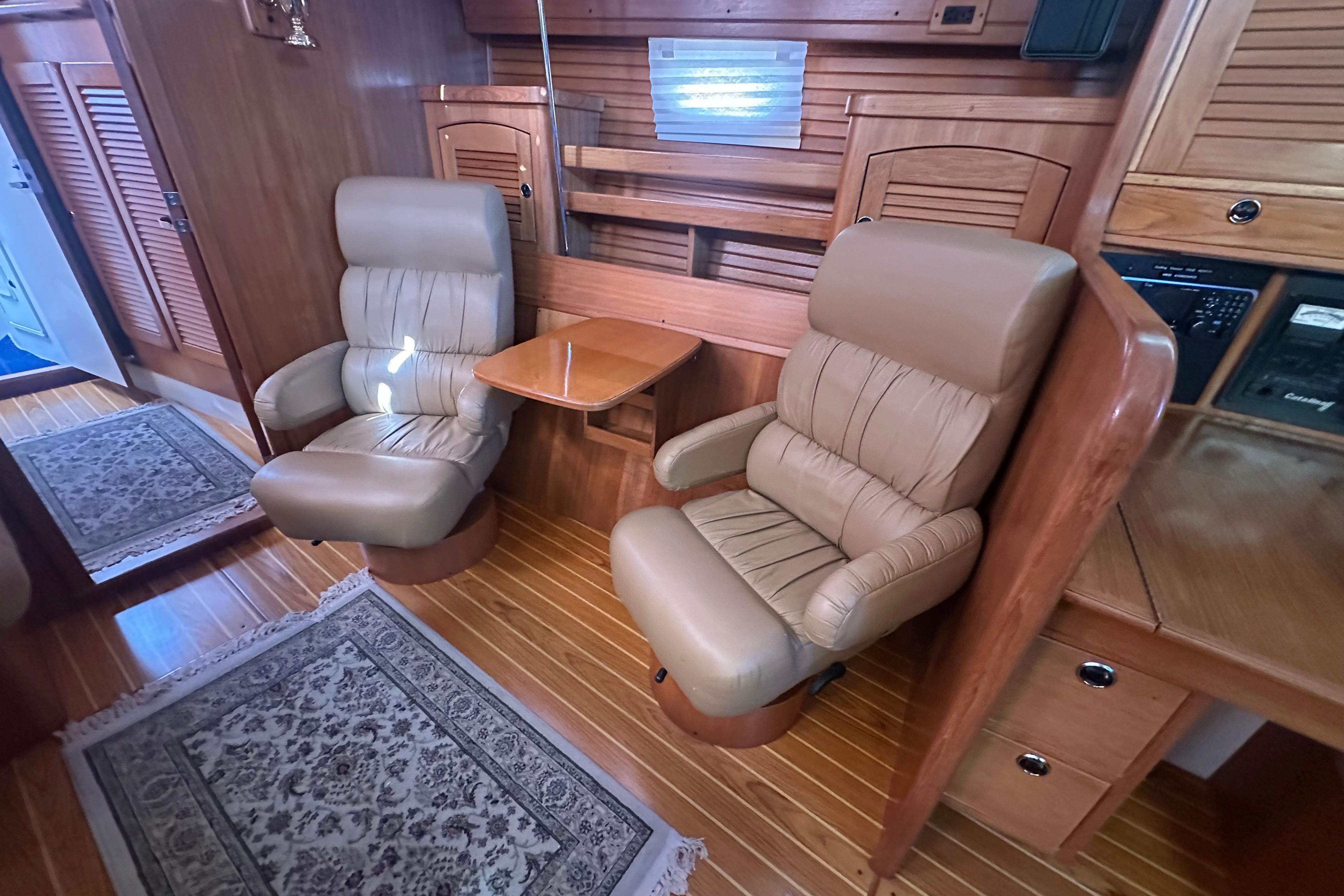 Luxurious interior of 2003 Catalina 470 yacht with leather chairs and wooden accents.