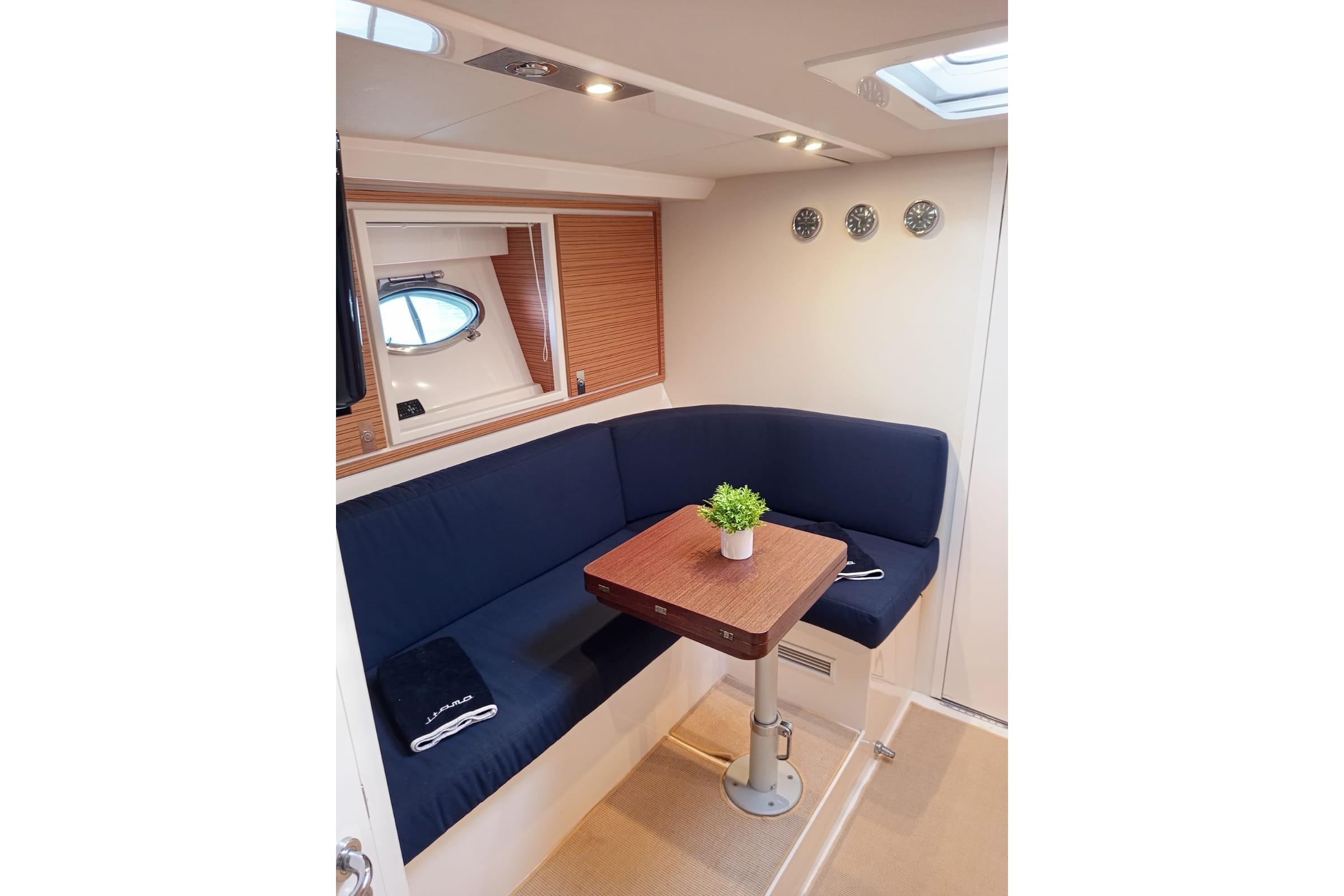 Interior of 2008 Itama 40 yacht with blue seating and wooden table.