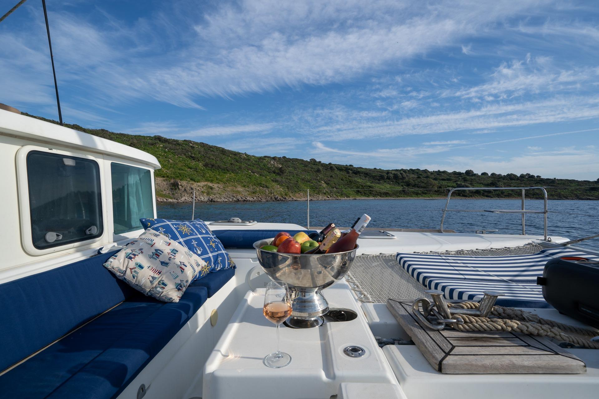 Lagoon 440 catamaran deck with fruit bowl, wine, and scenic ocean view, 2005 model.