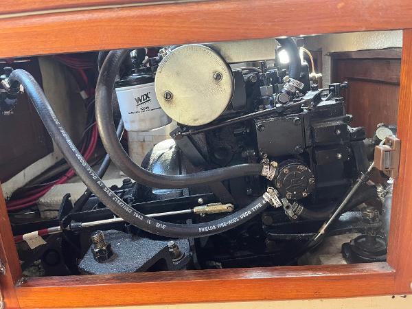 Engine compartment of a 1980 Catalina 30 sailboat, showcasing mechanical components and hoses.