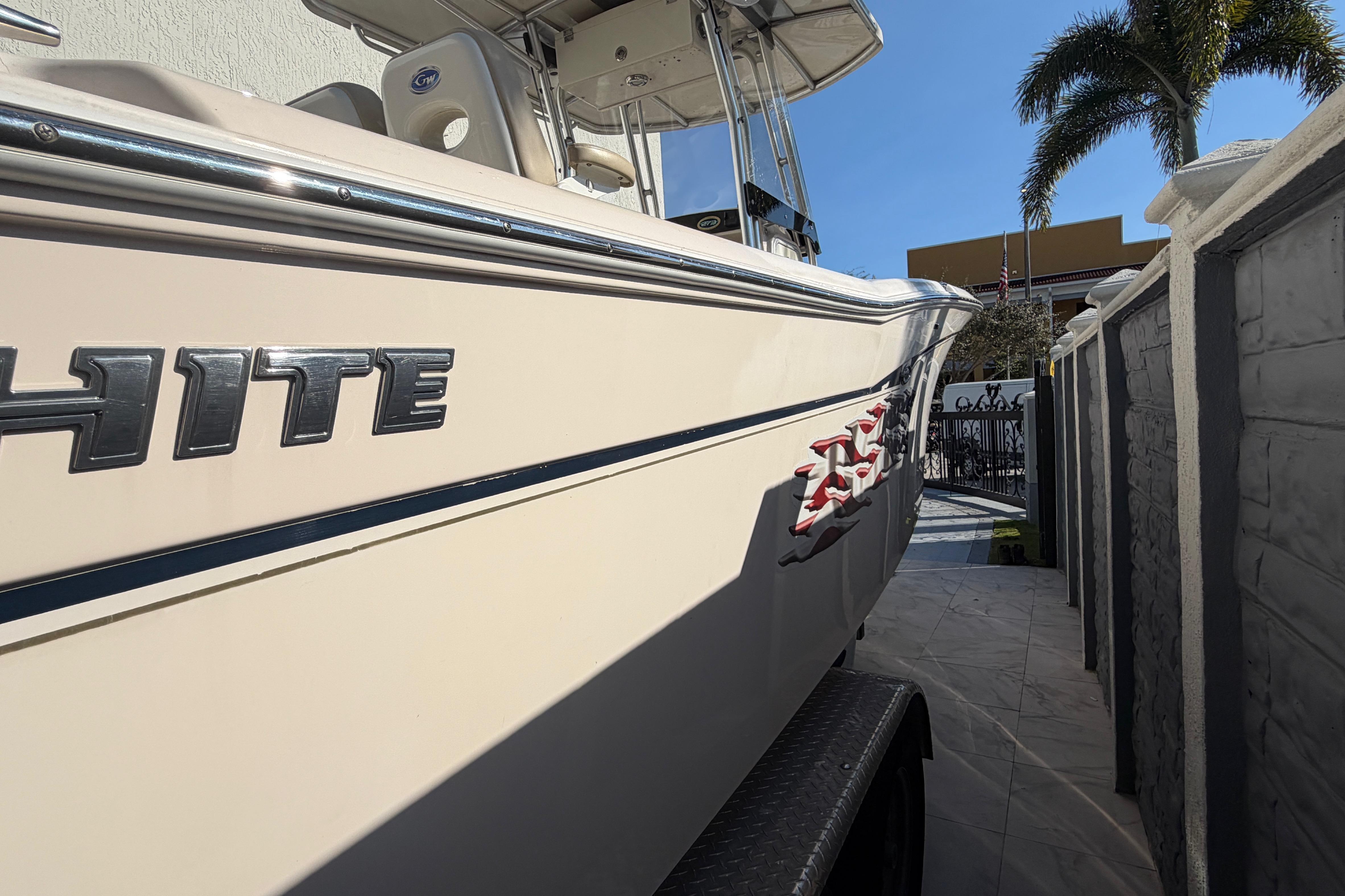 2004 Grady White 273 boat parked beside a wall under clear blue sky.