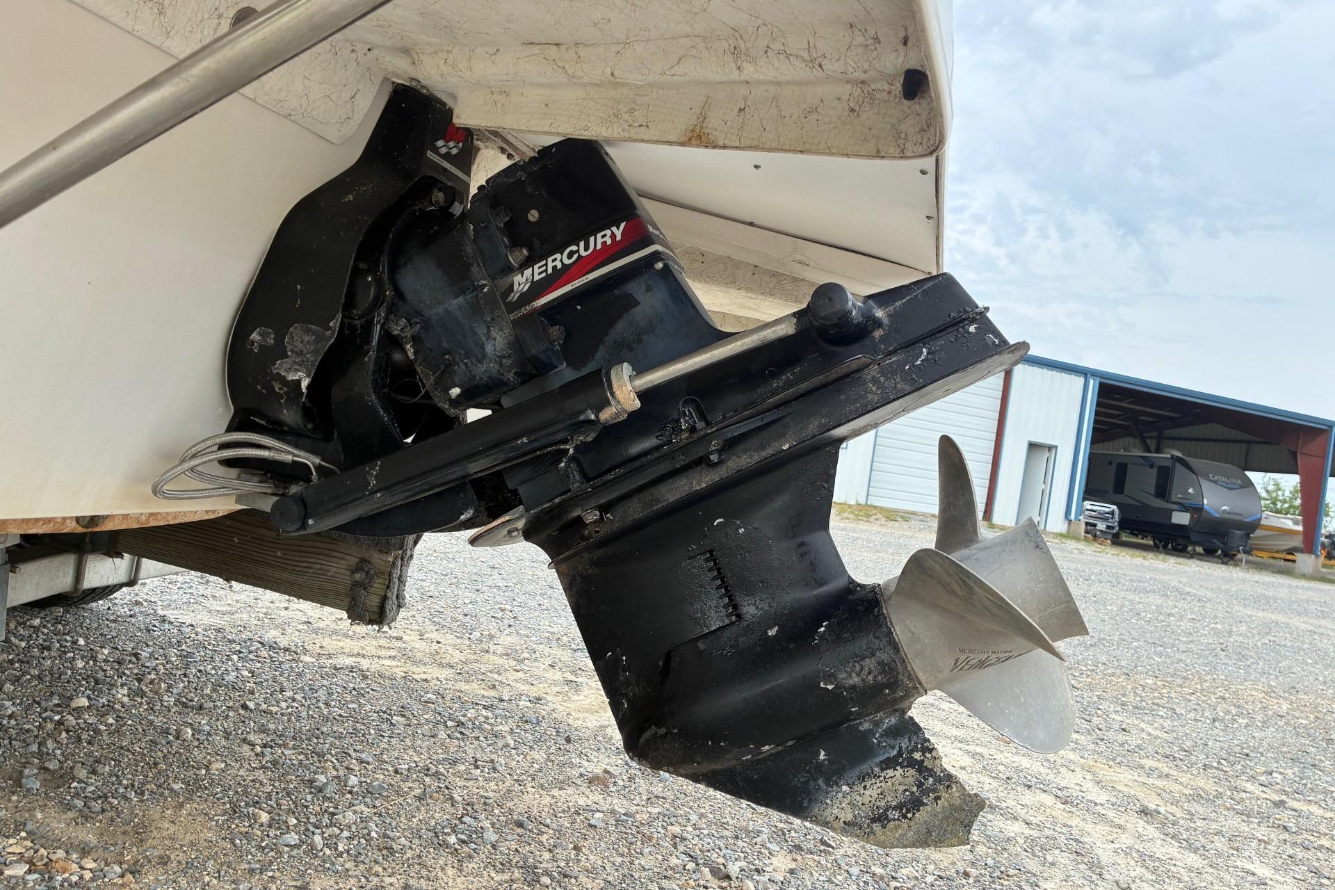 2003 Hurricane 234 SD boat with Mercury outboard motor, parked on gravel.