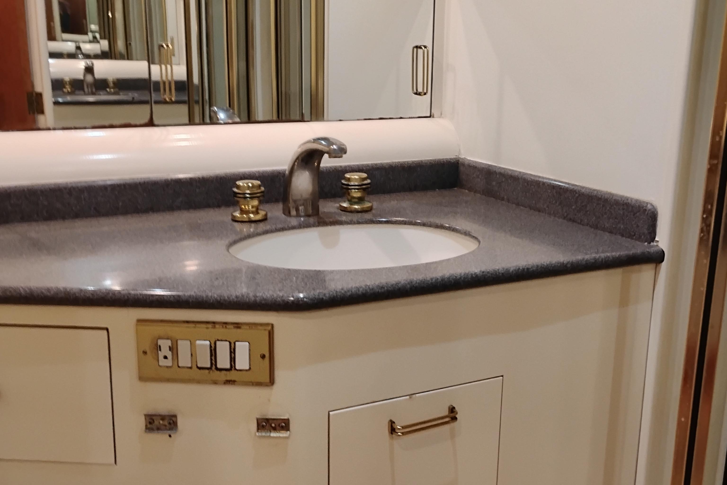 Bathroom sink area in 1995 Queenship 62 Pilothouse Motor Yacht, featuring modern fixtures.
