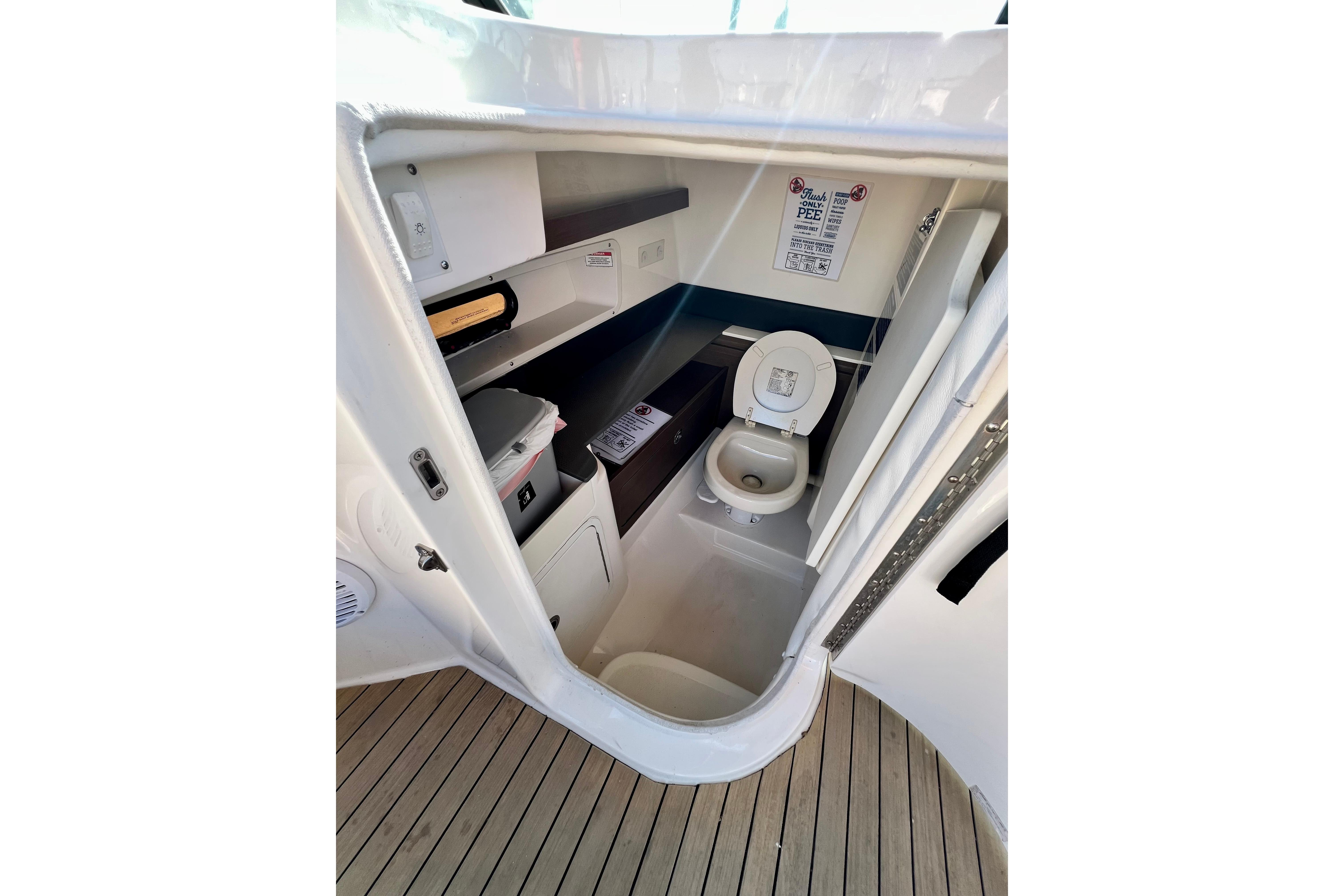 2016 Sea Ray 290 Sundeck Outboard boat interior bathroom with toilet and storage shelves.