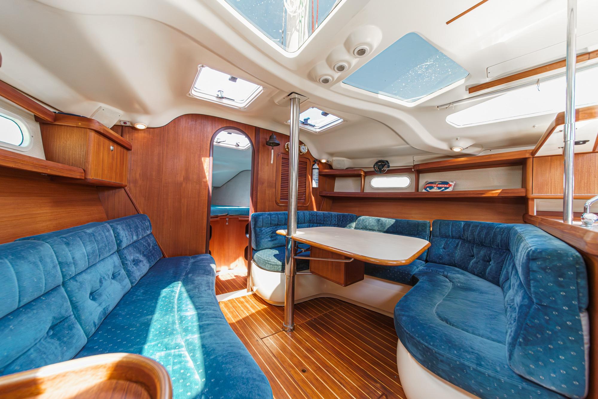 Interior of a 1996 Hunter 376 sailboat with blue seating and wooden accents.