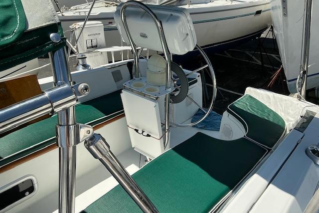 Cockpit of 2000 Beneteau Oceanis 321 sailboat with green seating and steering wheel.
