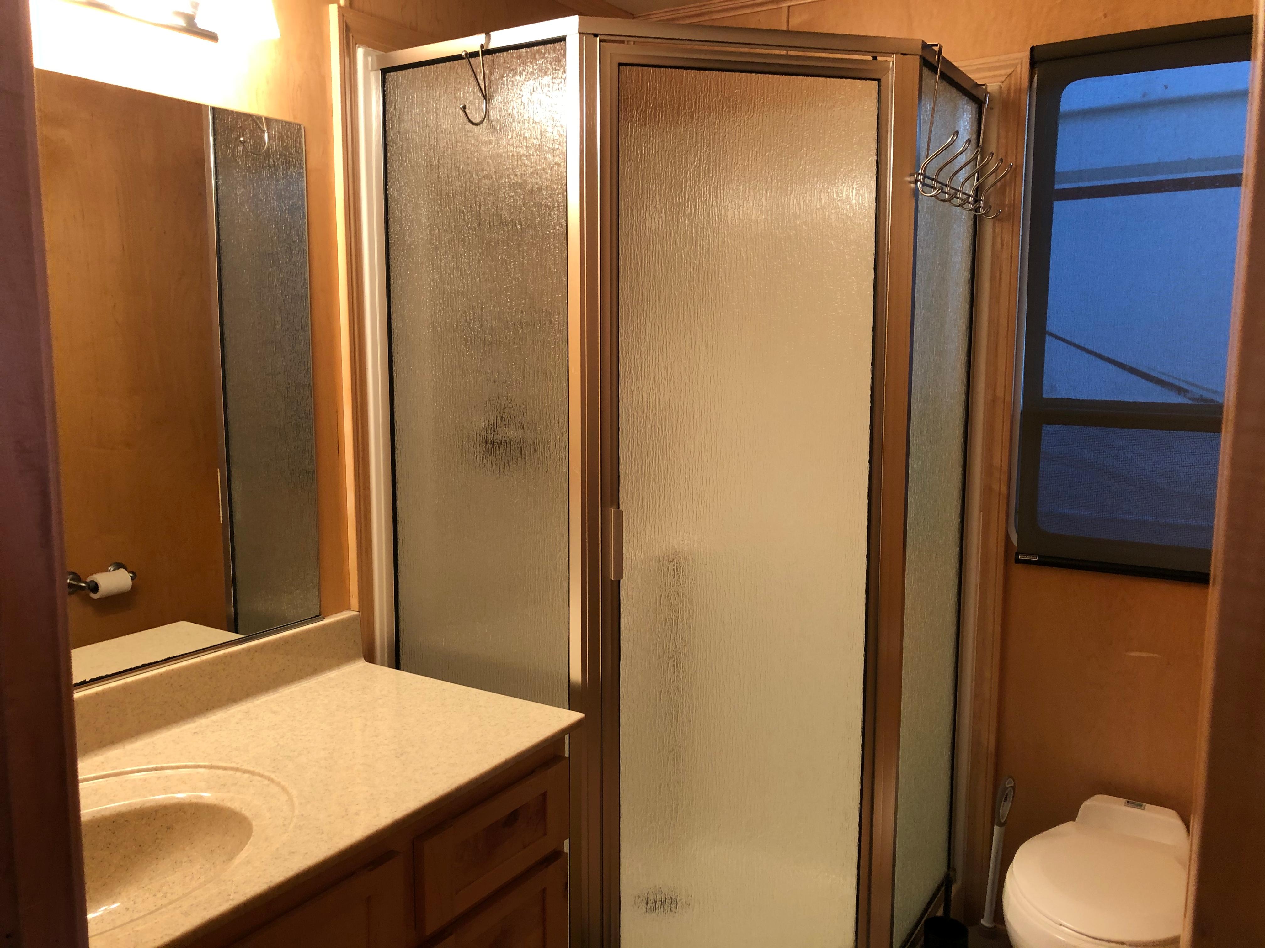 Modern RV bathroom with shower, sink, and toilet in a 2005 Custom Entourage Shares 20 & 35.