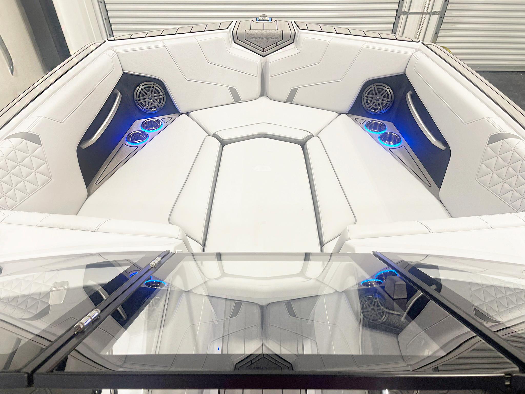 2025 Nautique Super Air Nautique GS24 interior with white seating, blue LED cup holders, and speakers.