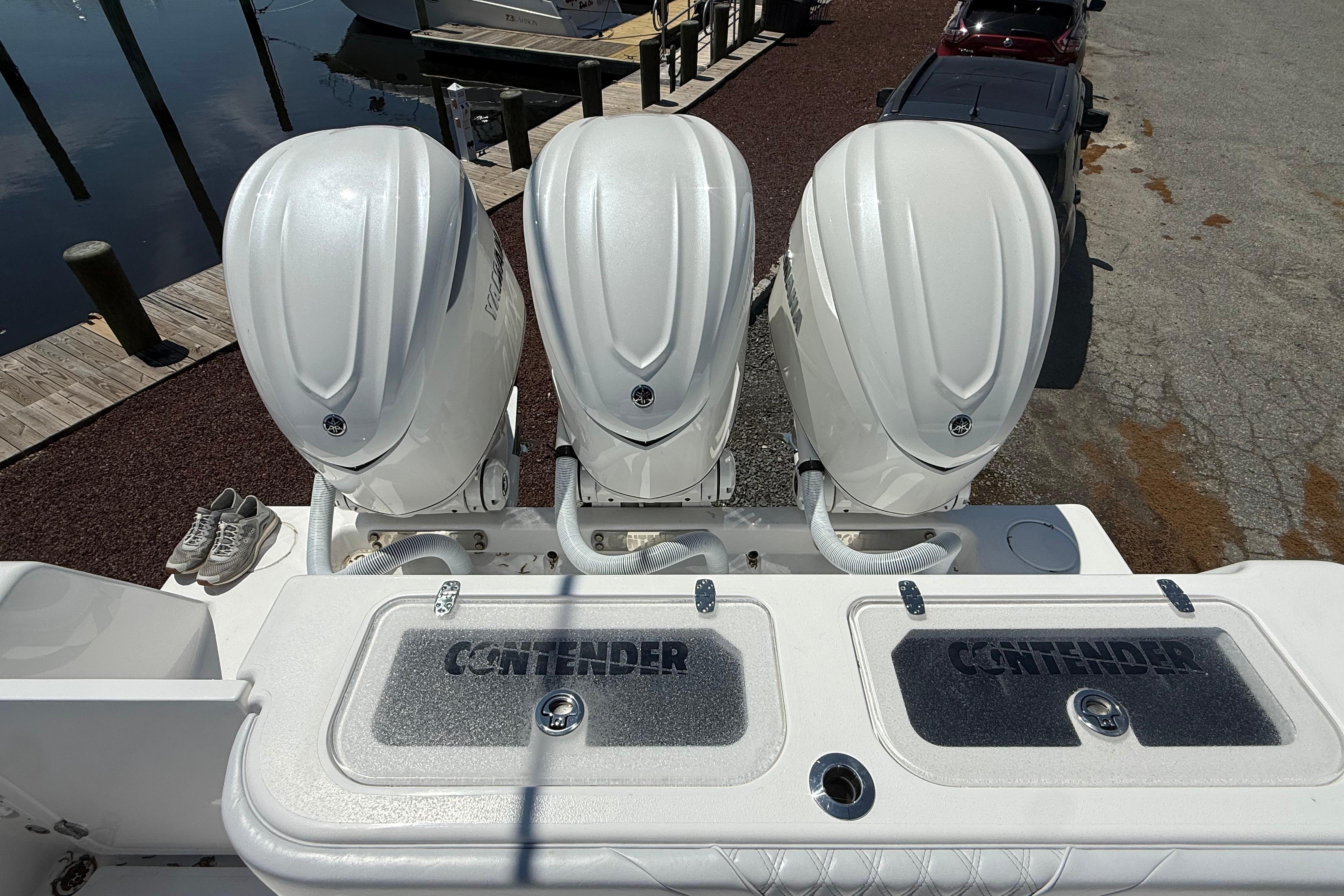 Triple outboard engines on a 2026 Contender 39 ST boat at a dock.