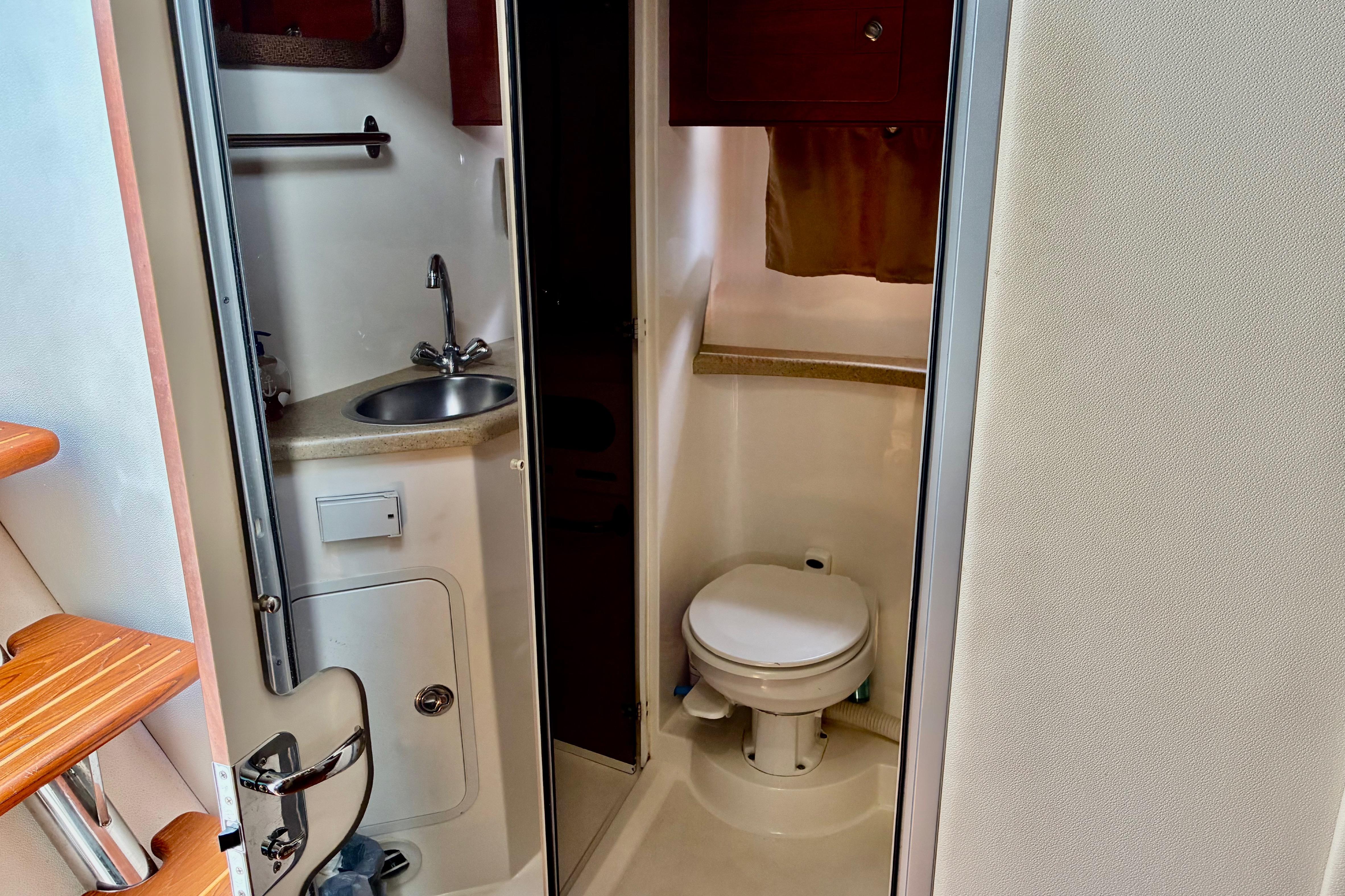2006 Rinker 390 Express Cruiser bathroom with sink, toilet, and wooden steps.