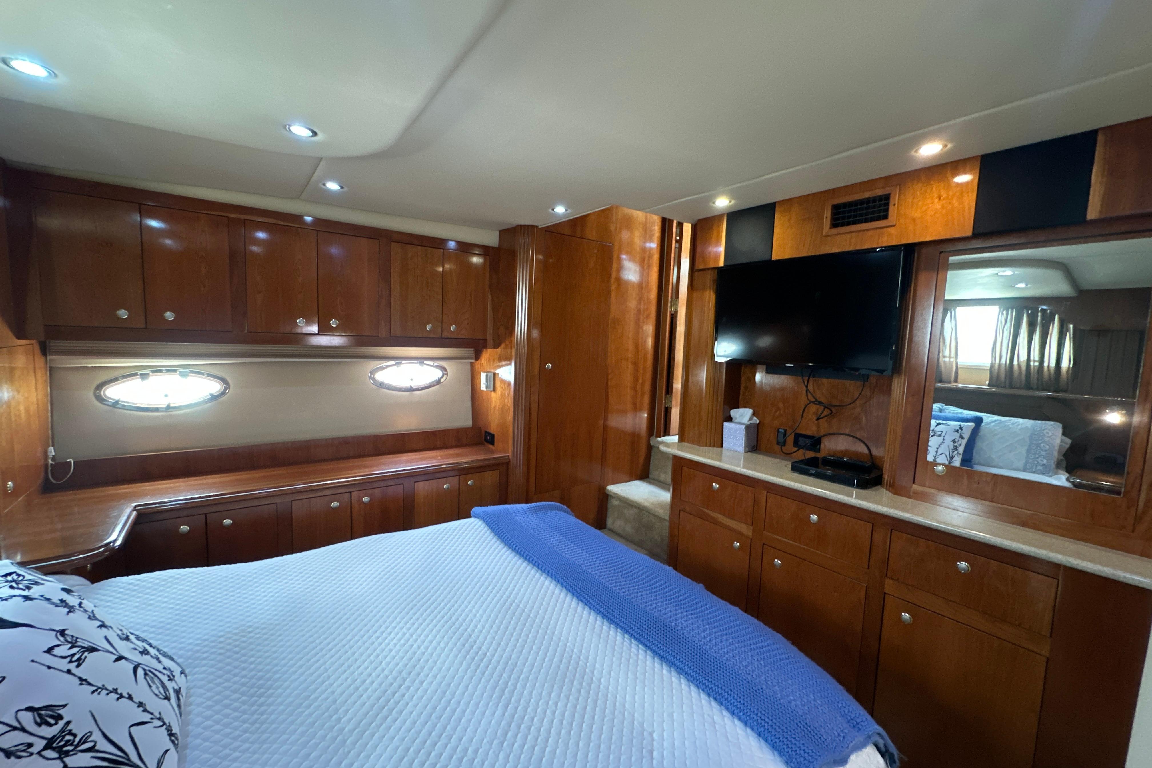 Luxurious 2004 Cruisers Yachts 405 Express Motoryacht bedroom with wood cabinetry and modern amenities.