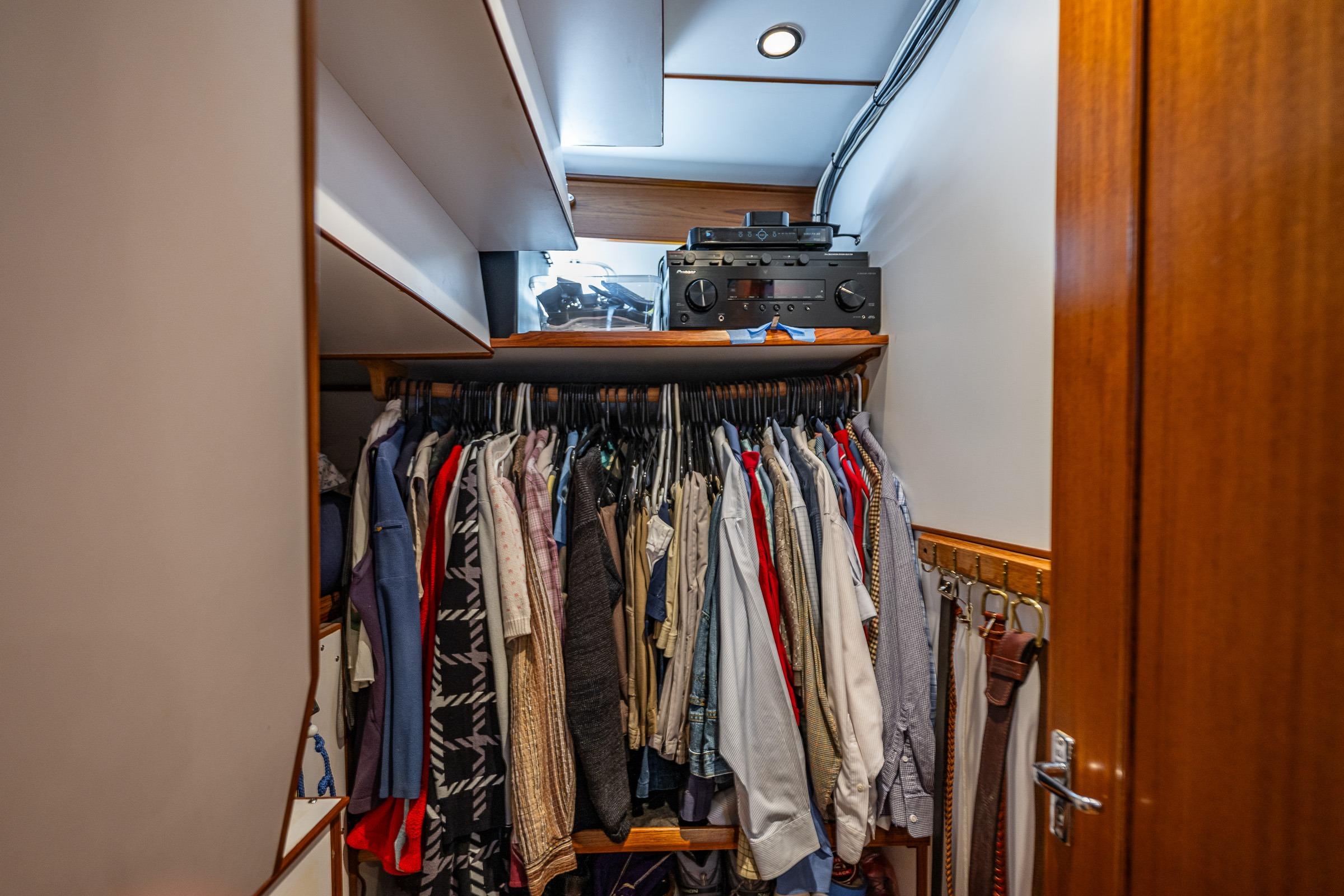 Closet with clothes and audio equipment in 2007 DeFever 56 yacht interior.