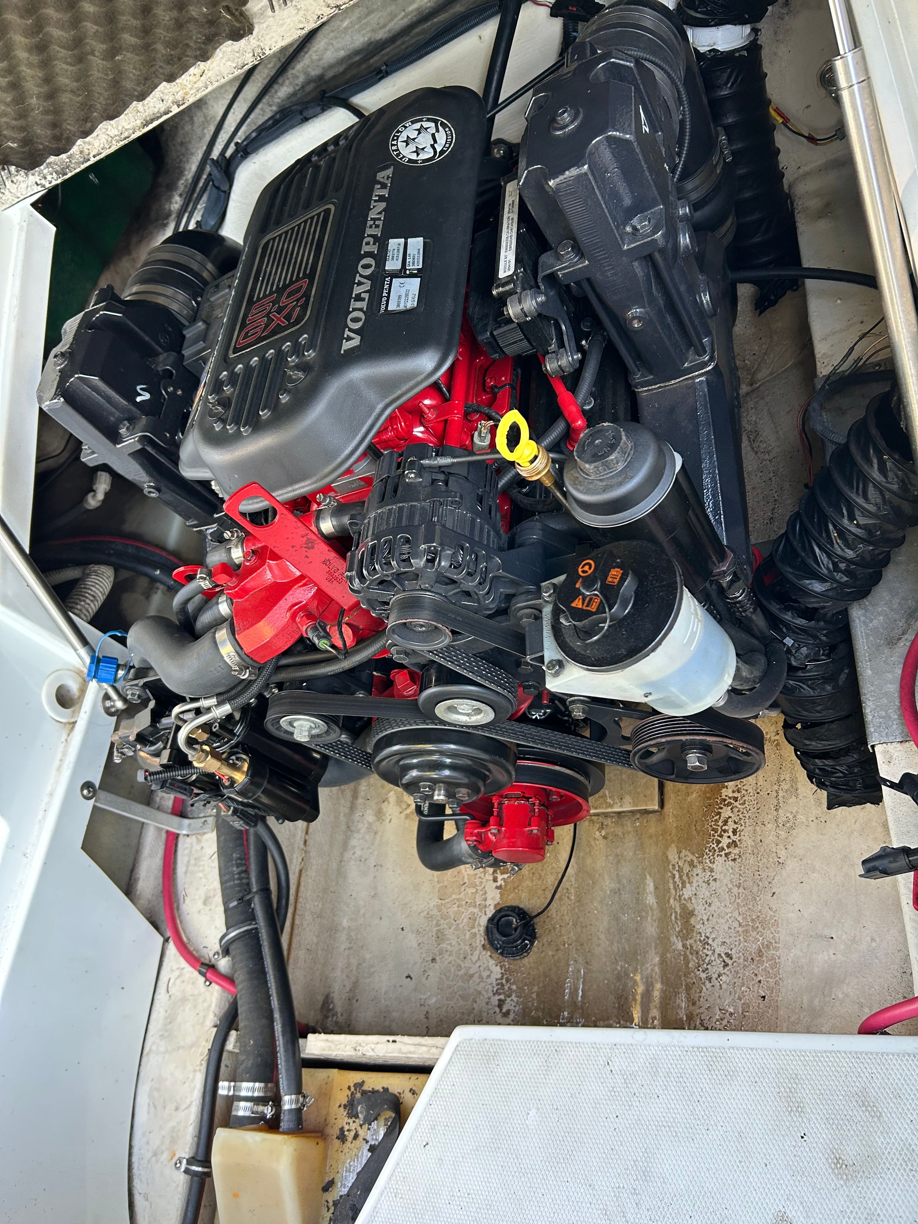 A Volvo Penta engine in a boat's engine compartment, surrounded by hoses and cables.