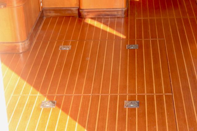 Teak wood flooring on 1996 Nordhavn 46 yacht, featuring metal fixtures and warm tones.