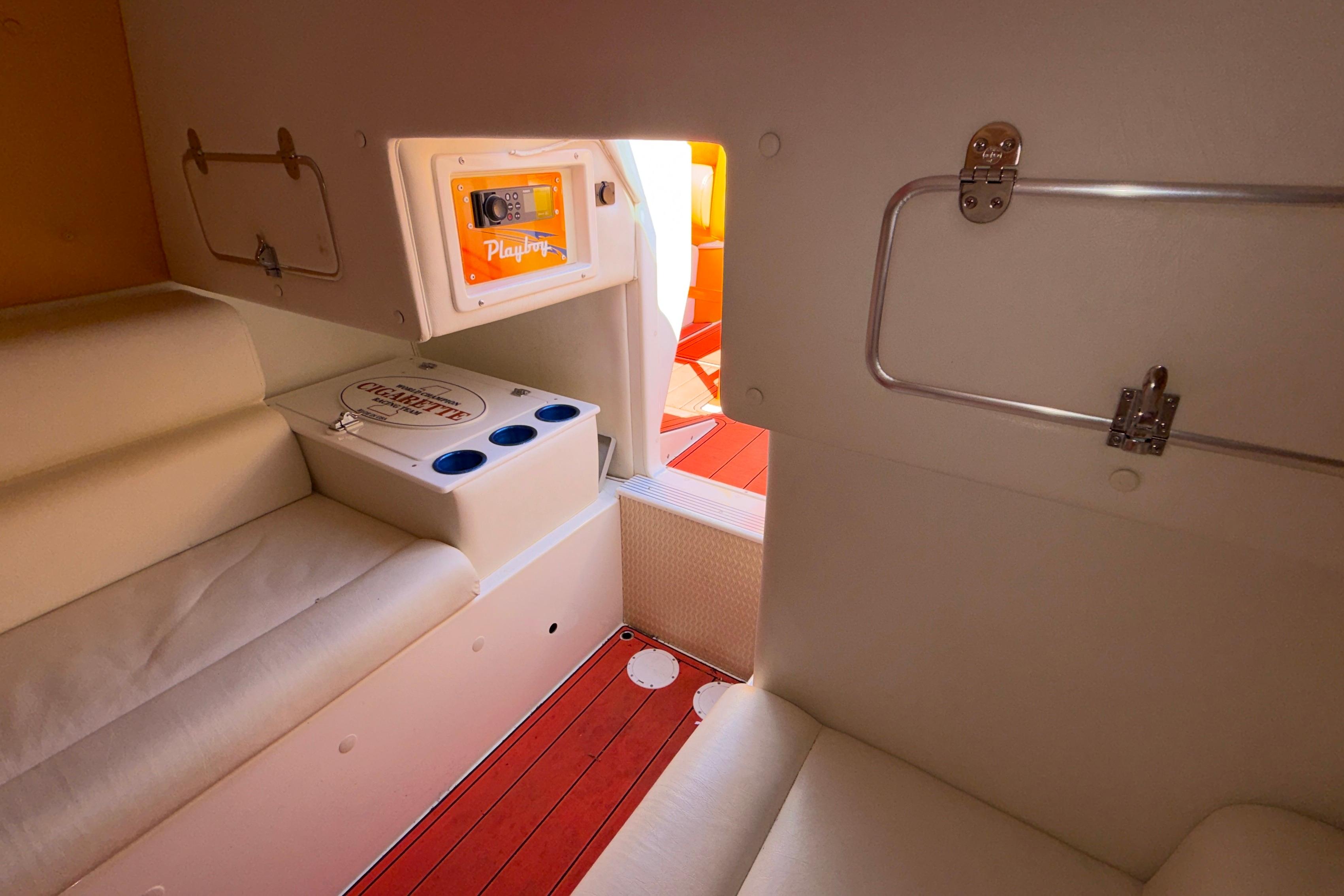 Interior of 2002 Cigarette 35' Cafe Racer boat with white seating and storage compartments.
