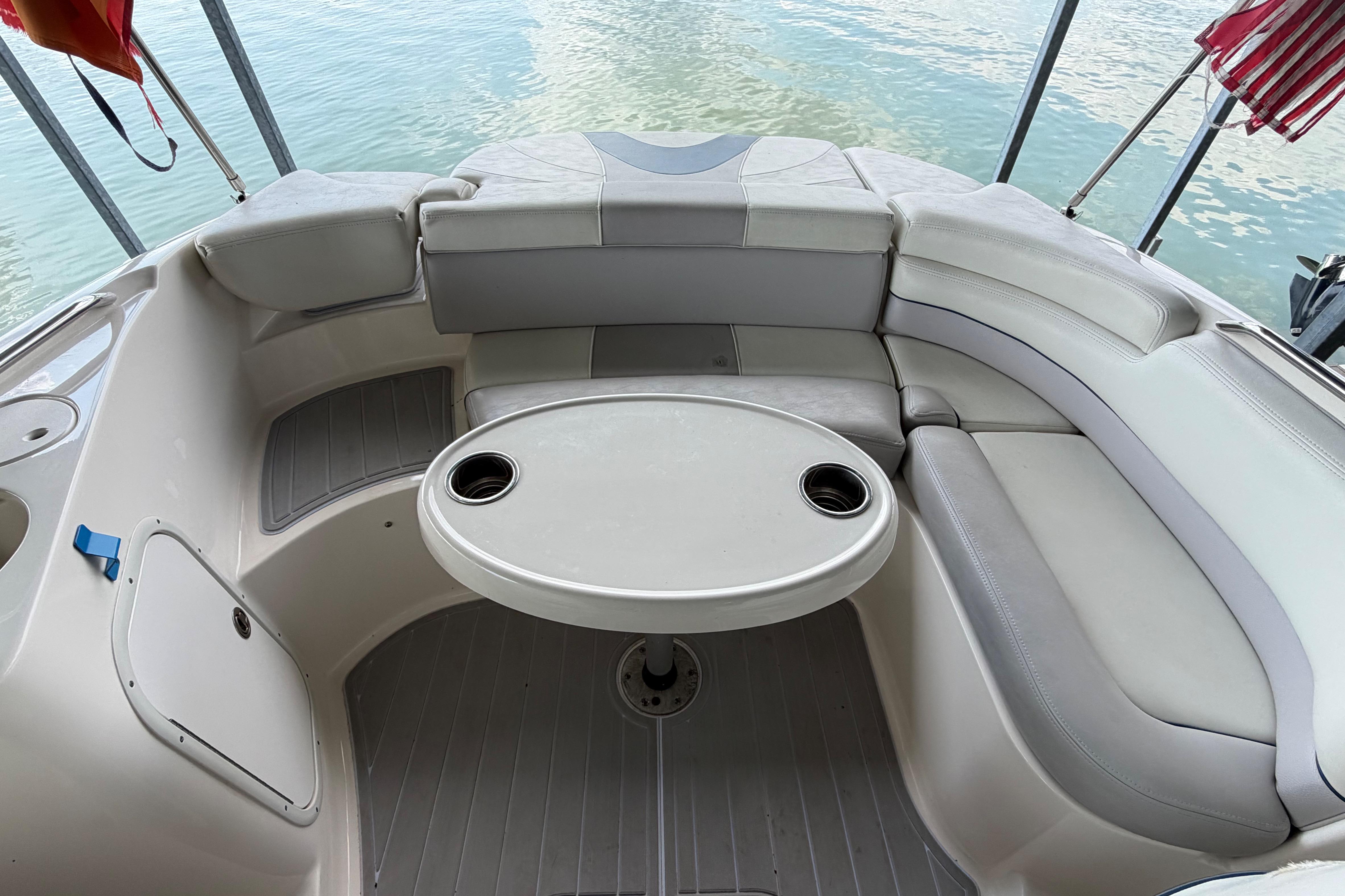 2010 Bryant 255 boat interior with curved seating and table on calm water.