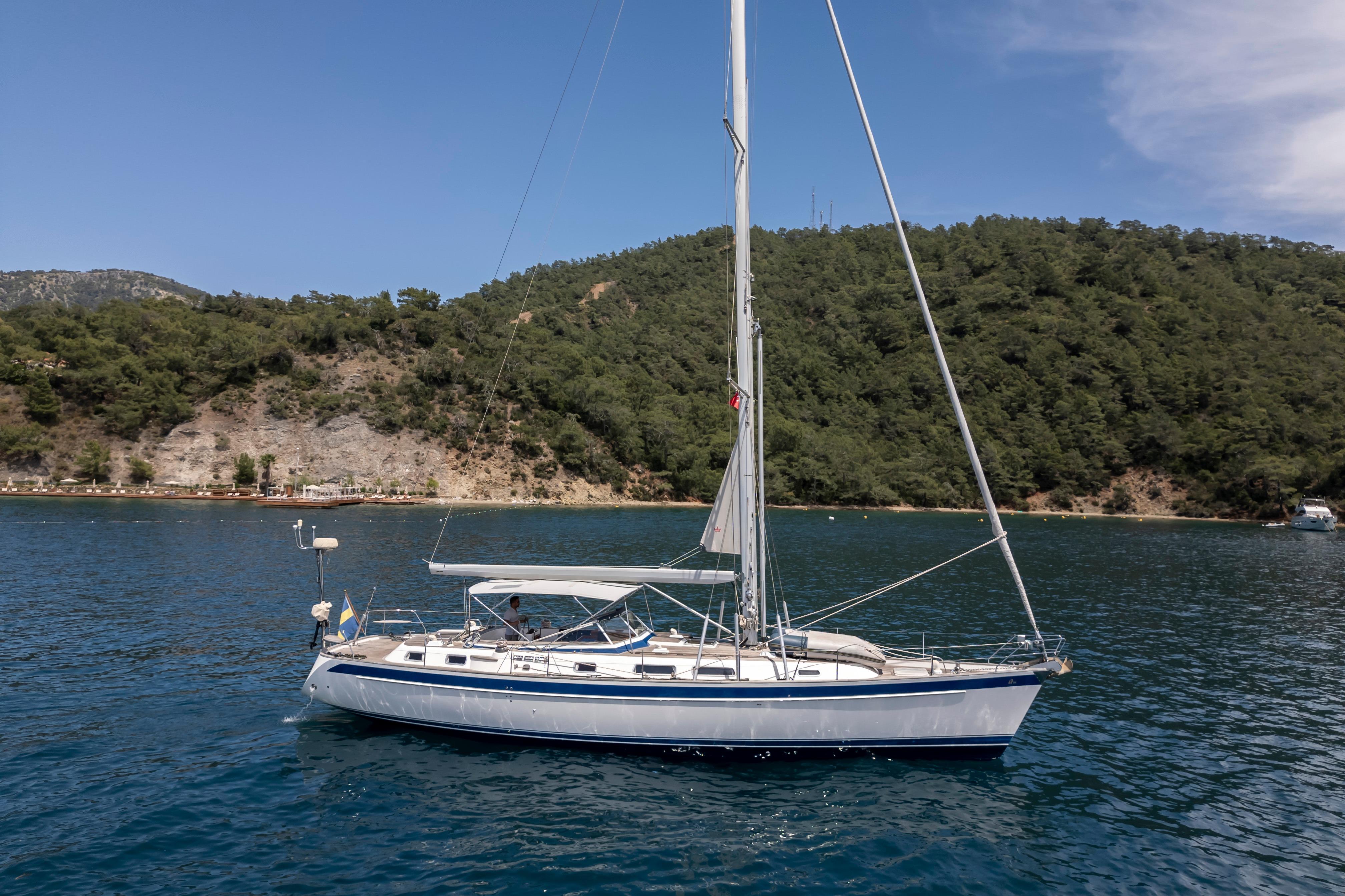 Sailing yacht Hallberg-Rassy 54, 2007 model, anchored in scenic coastal waters.