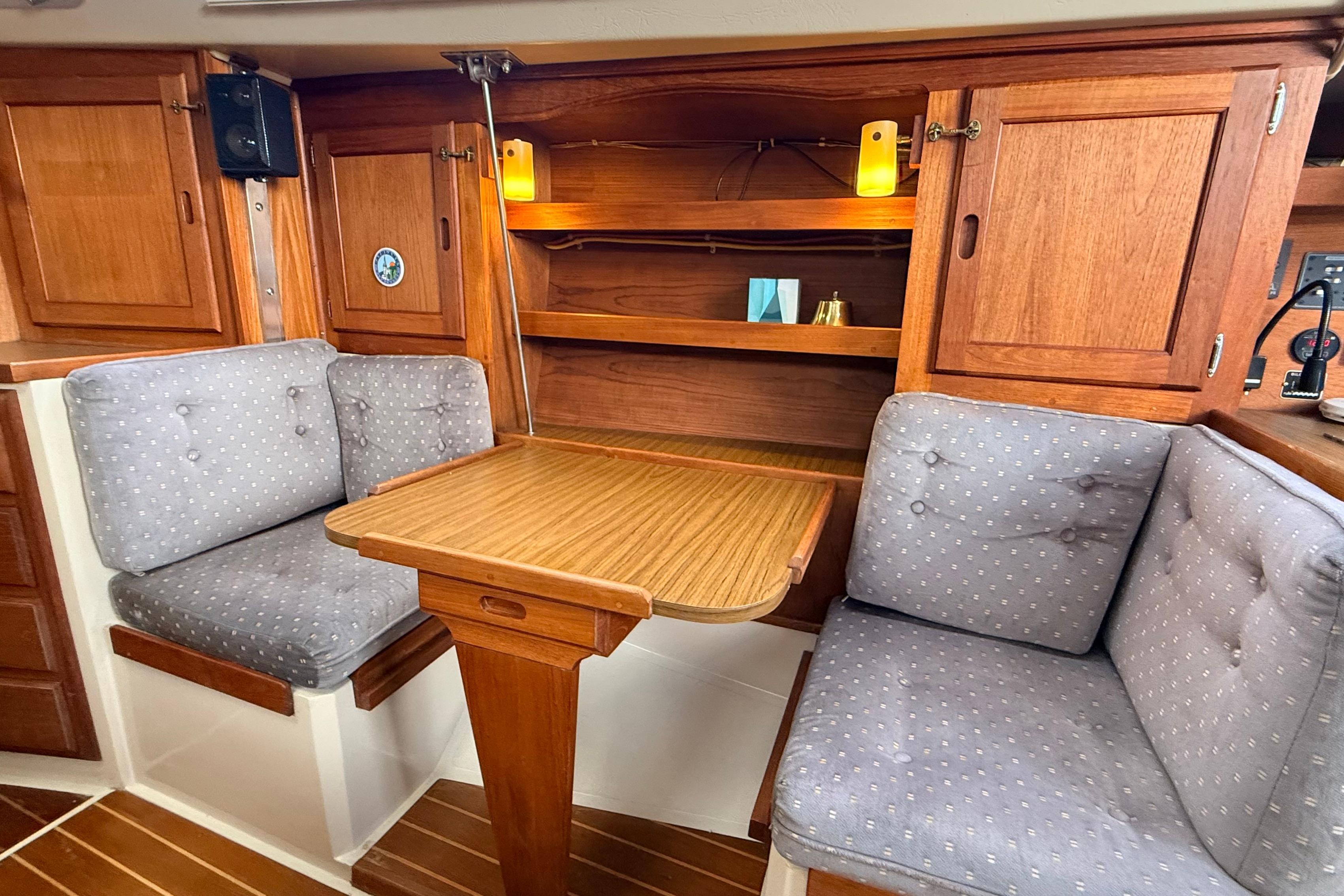 Interior of 1985 Catalina 36 sailboat with cozy seating and wooden cabinetry.