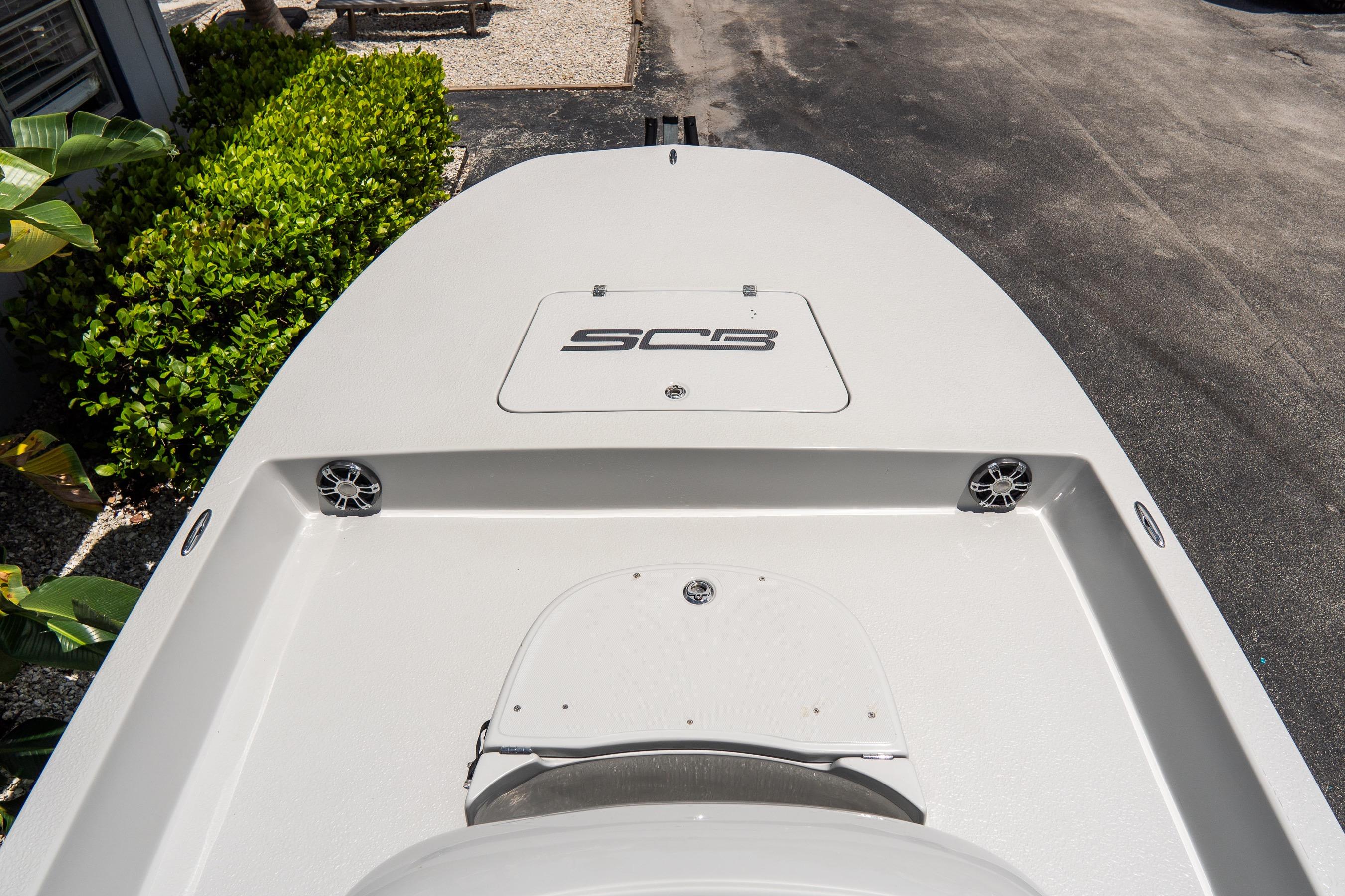 2021 SCB S22 boat deck with storage hatch and speakers, surrounded by greenery.