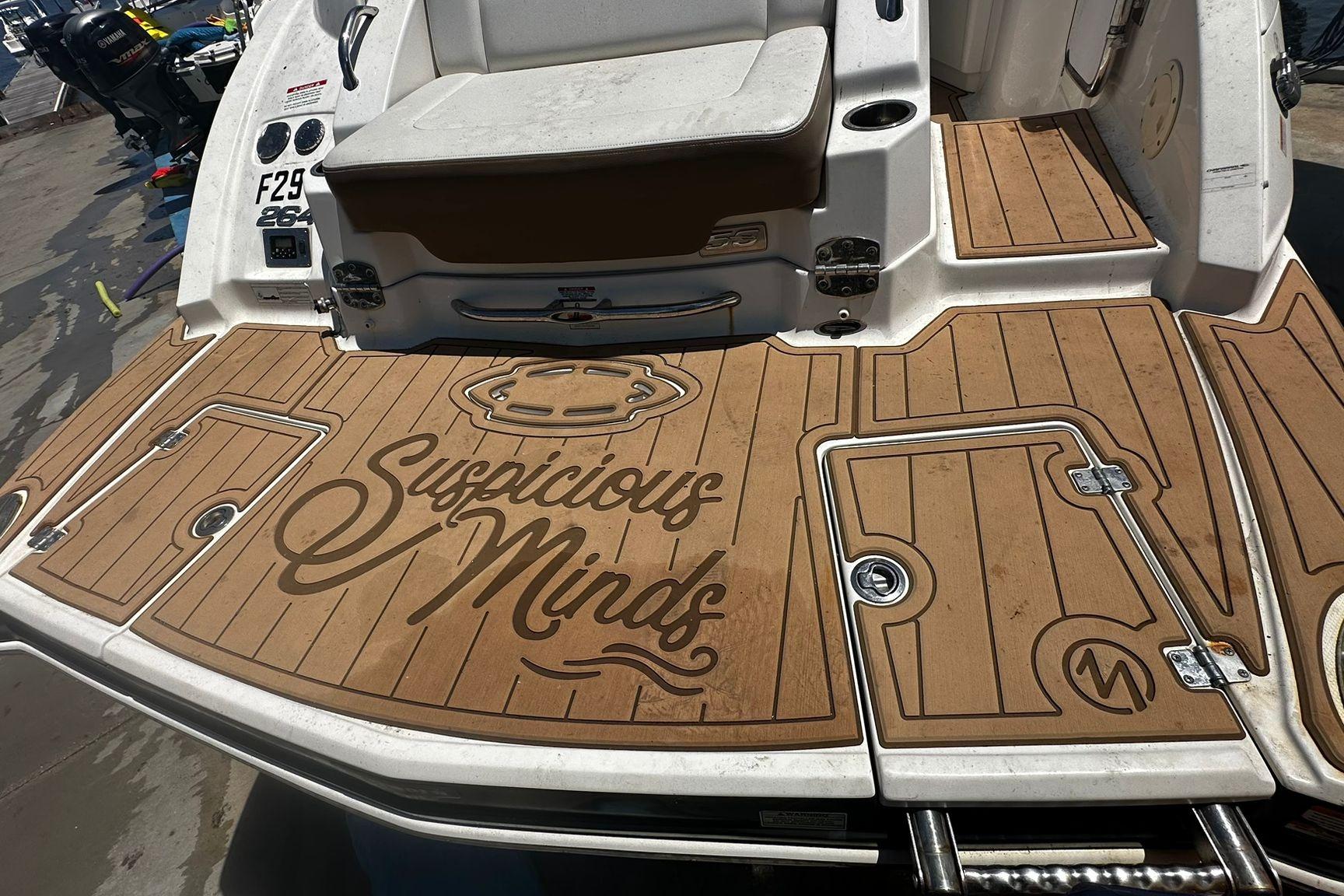 2015 Chaparral 264 Sunesta boat deck with "Suspicious Minds" text, featuring teak-style flooring.