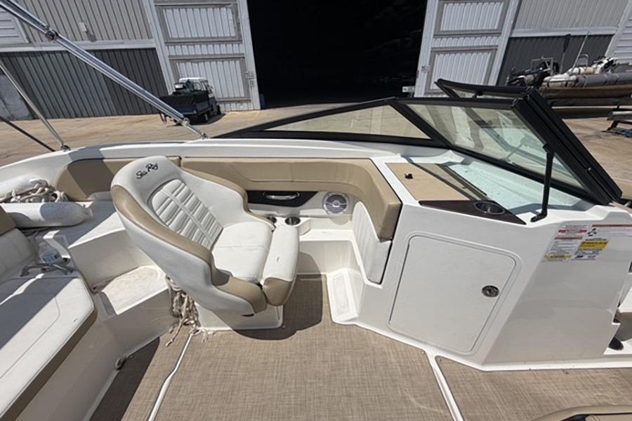 2018 Sea Ray SPX 190 boat interior with beige seating and dashboard, docked in a marina.