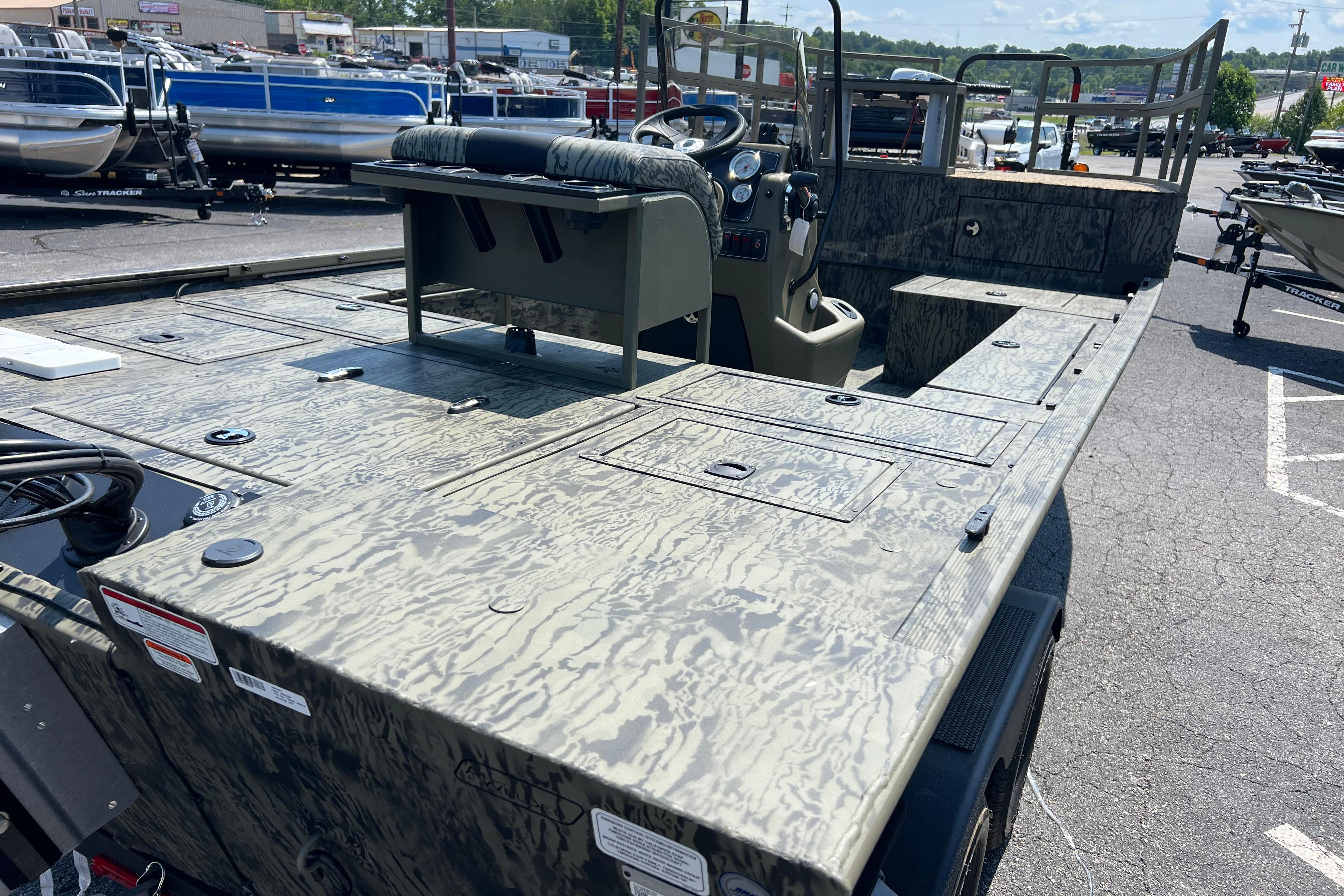 2026 Tracker Grizzly 2072 CC Sportsman Kicker boat with camouflage design in a parking lot.