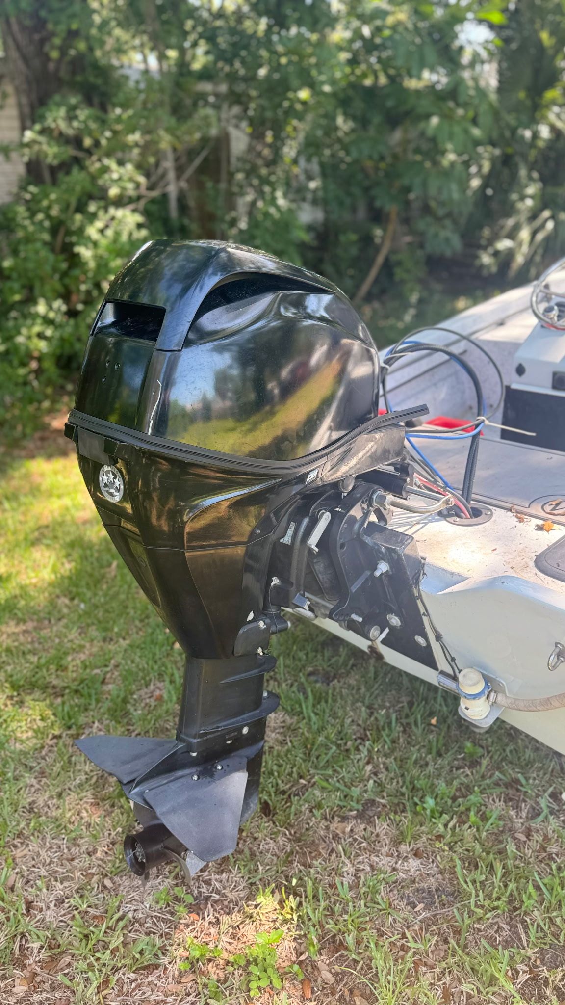 An outboard motor on a 1974 McKee Craft Skiff, parked on grass.