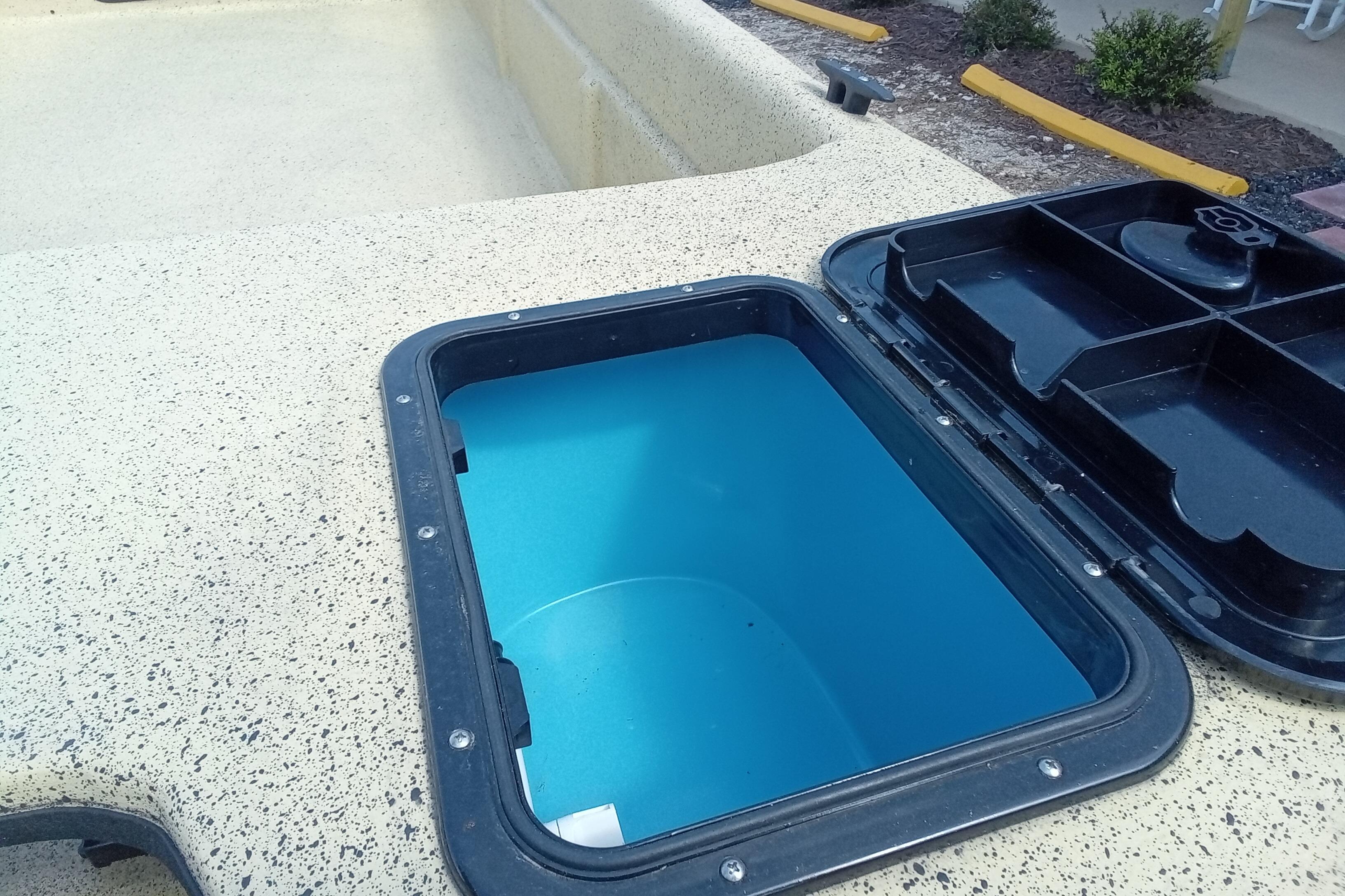 Open storage compartment on 2025 Fibercraft F17 boat, showcasing interior design.