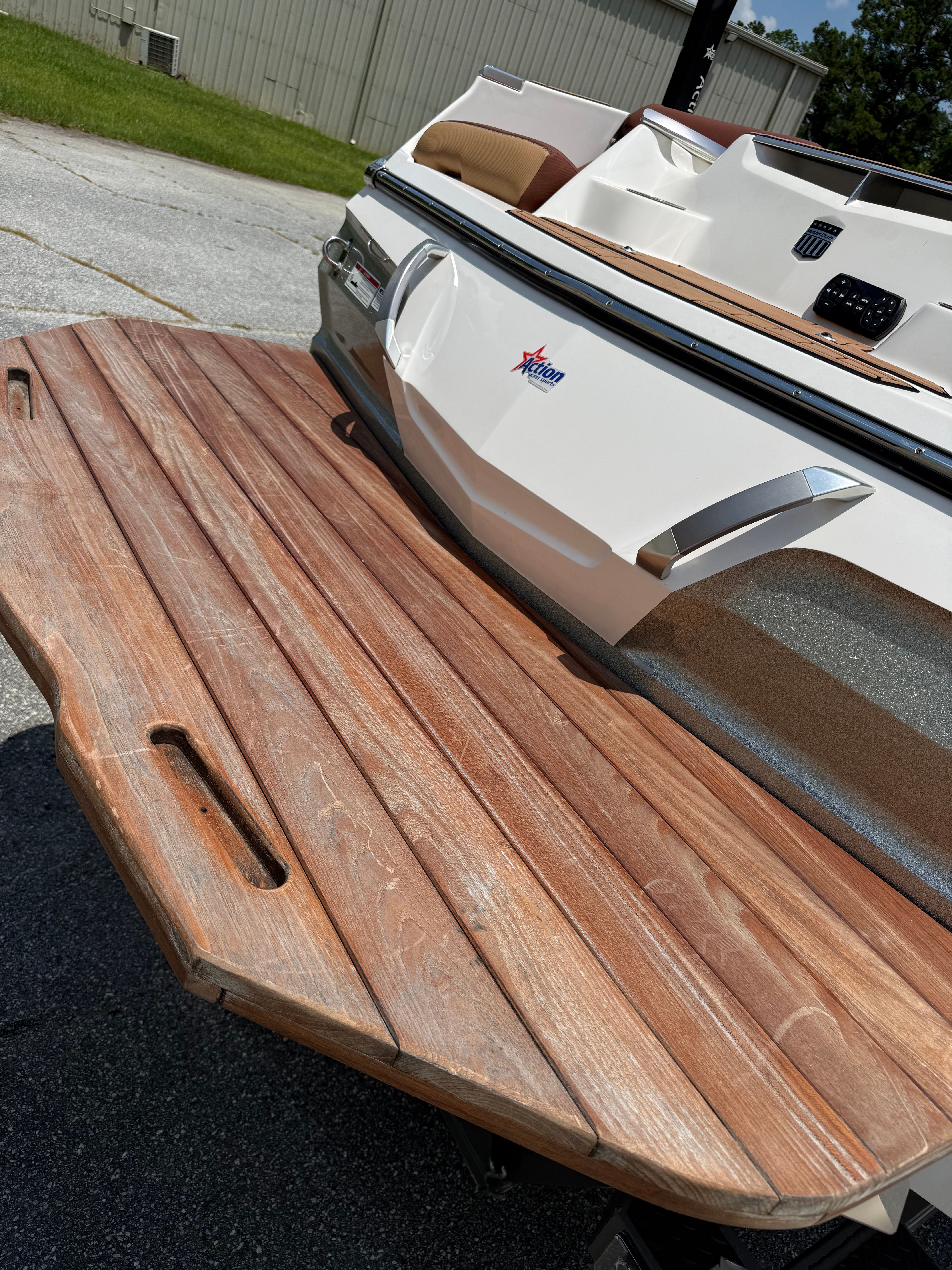 The image shows the stern of a MasterCraft X24 boat with a wooden swim platform.