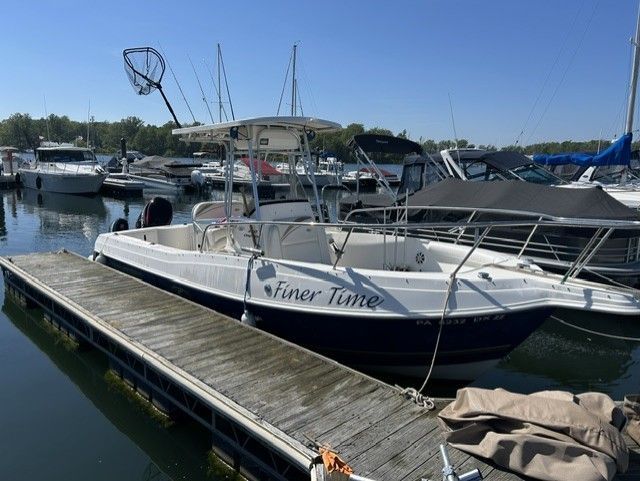 A 2000 Aquasport Osprey 250 boat docked in a marina on a sunny day.
