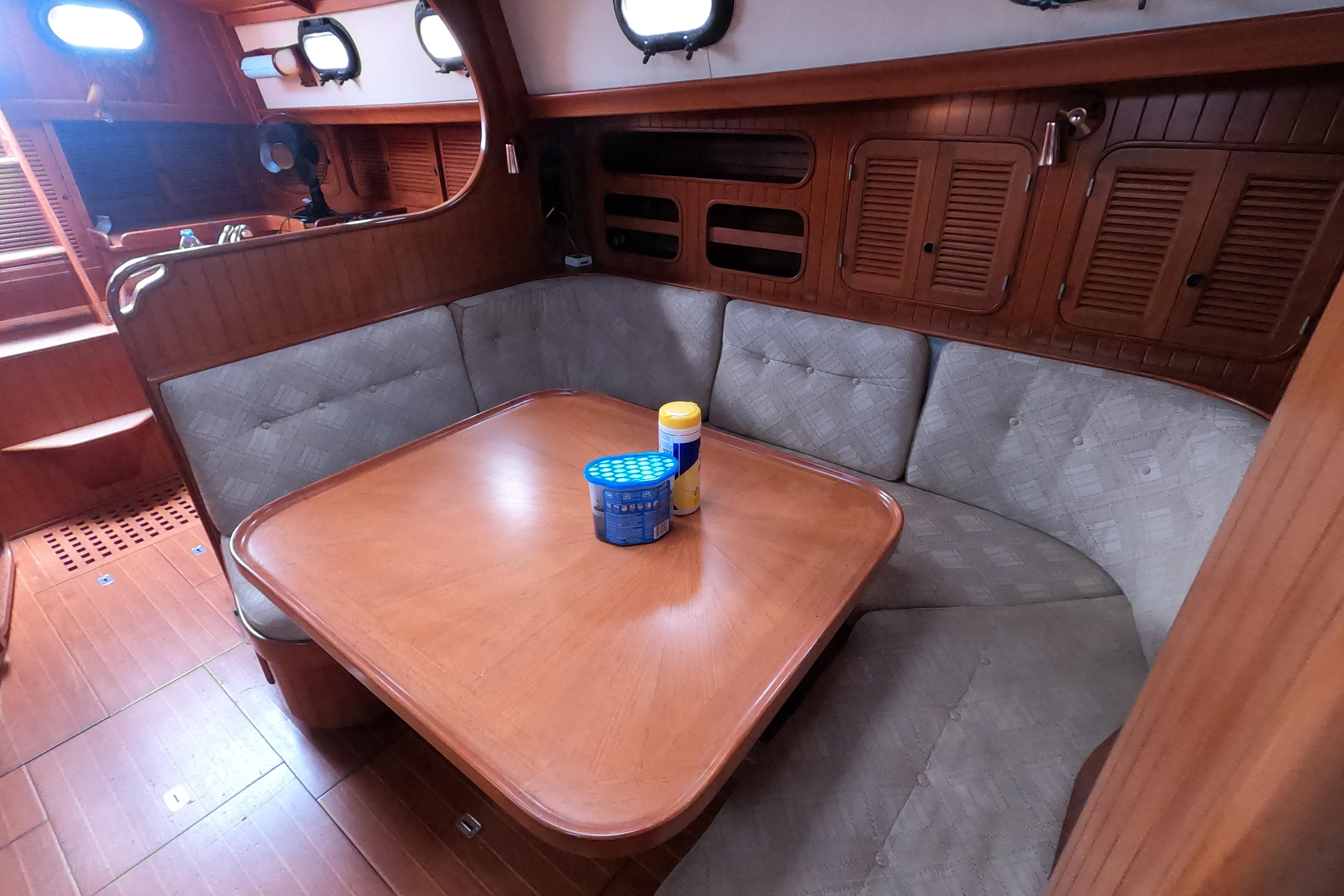 Interior of 1986 Ta Shing Baba 40 sailboat with wooden dining area and cushioned seating.