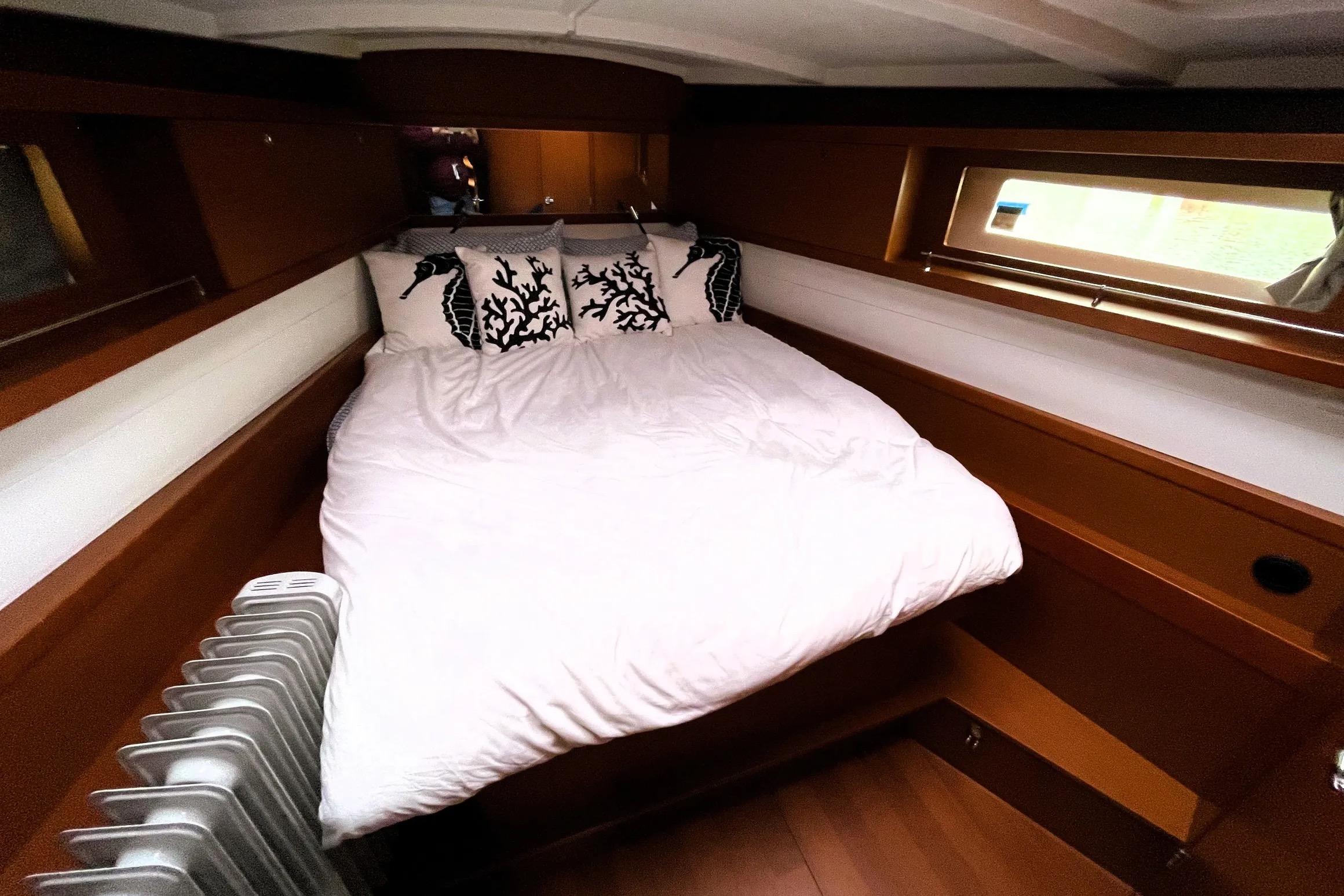 Cozy cabin interior of 2018 Beneteau Oceanis 45 yacht with bed and window.