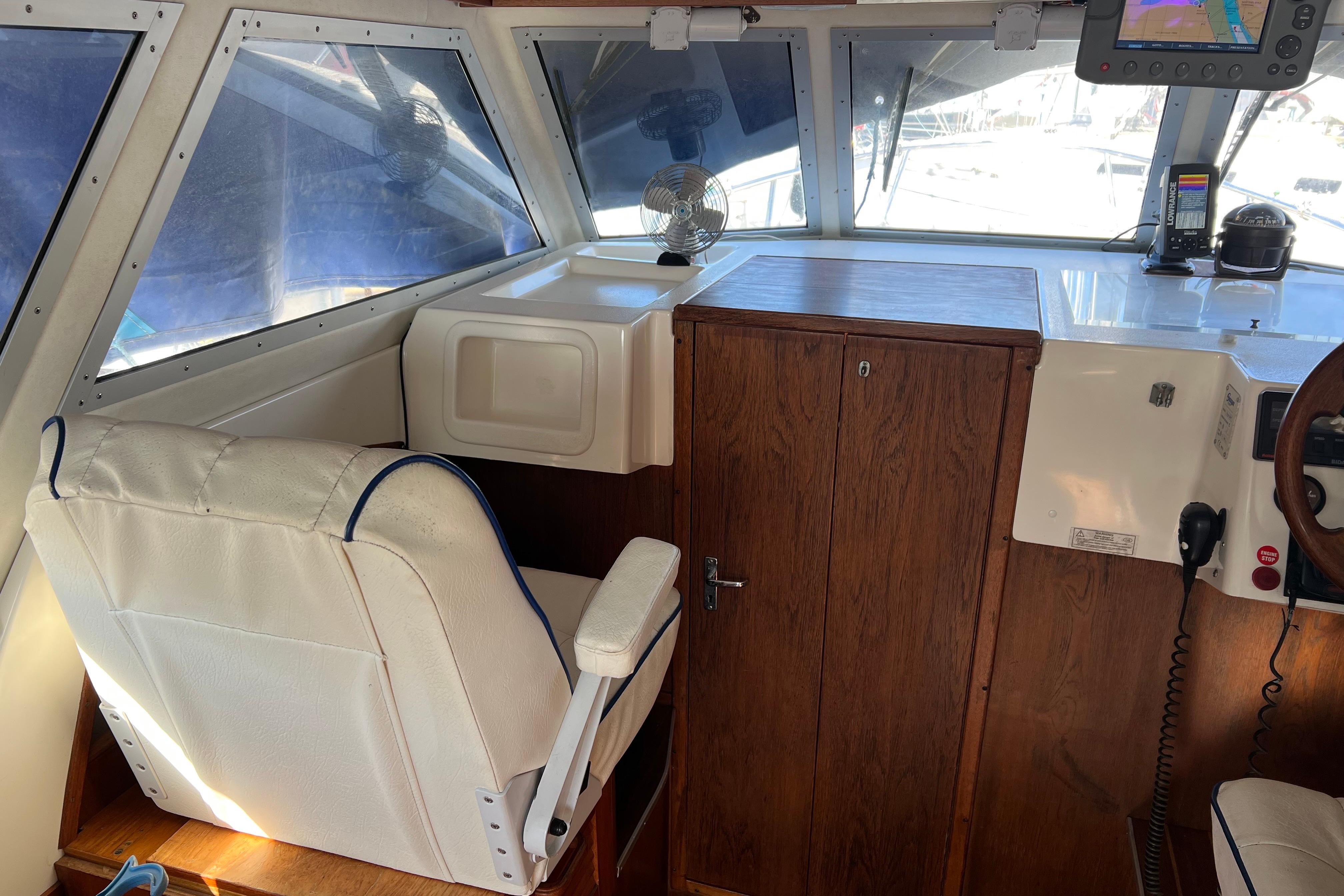 Interior of 1999 Saga 26 boat with white seating and wooden cabinetry.