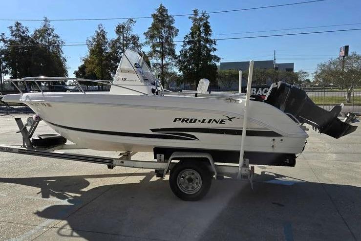 2001 Pro-Line 19 Sport boat on trailer, parked outdoors in sunny setting.