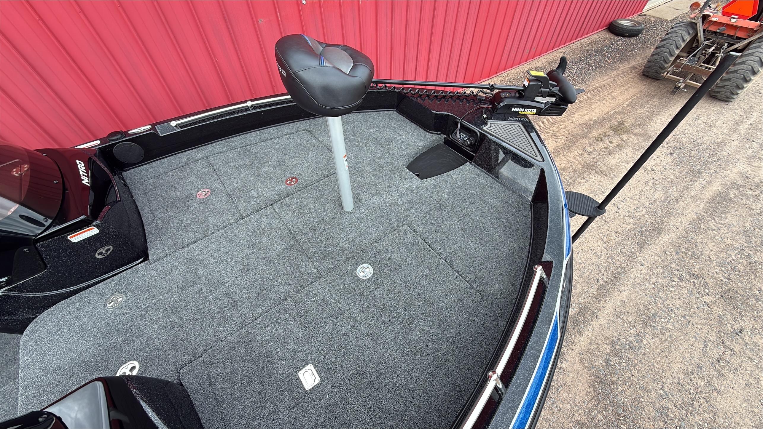 2025 Nitro ZV19 boat deck with seating and trolling motor, parked near a red wall.