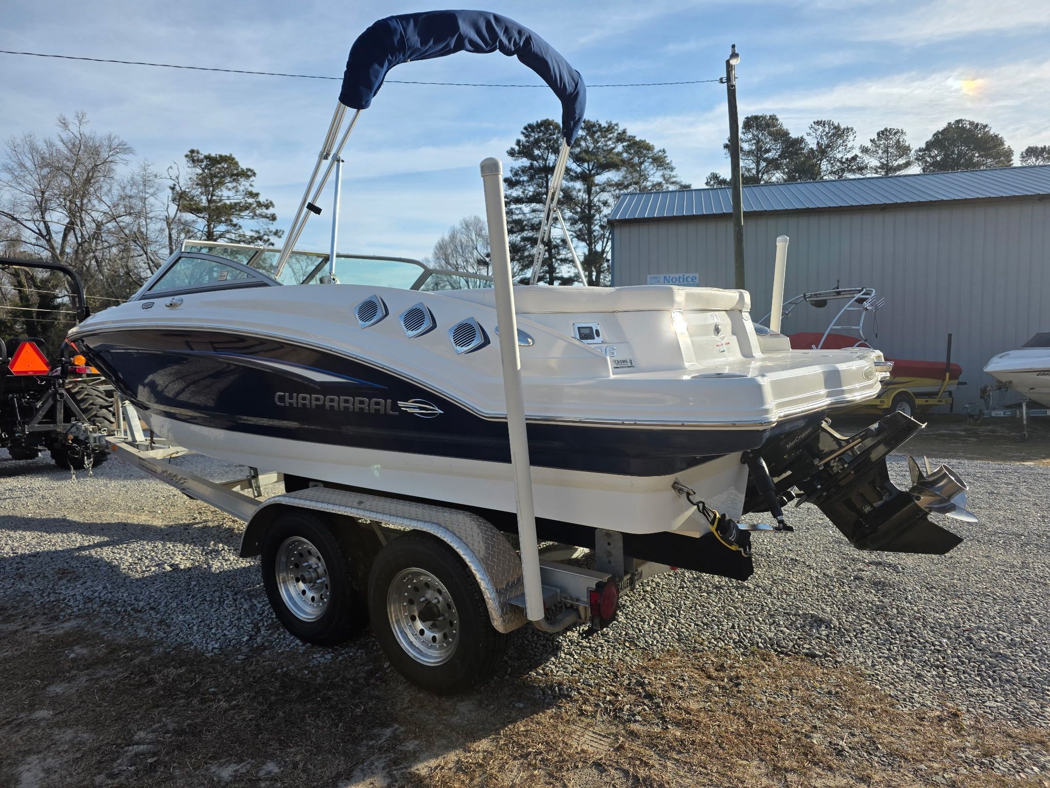 A Chaparral 206 SSi boat on a trailer, surrounded by trees and buildings.