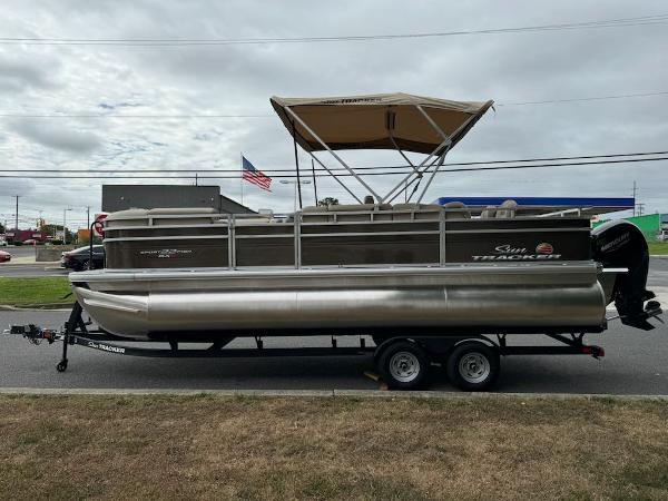 2025 Sun Tracker SportFish 22 XP3 pontoon boat on trailer, parked outdoors.
