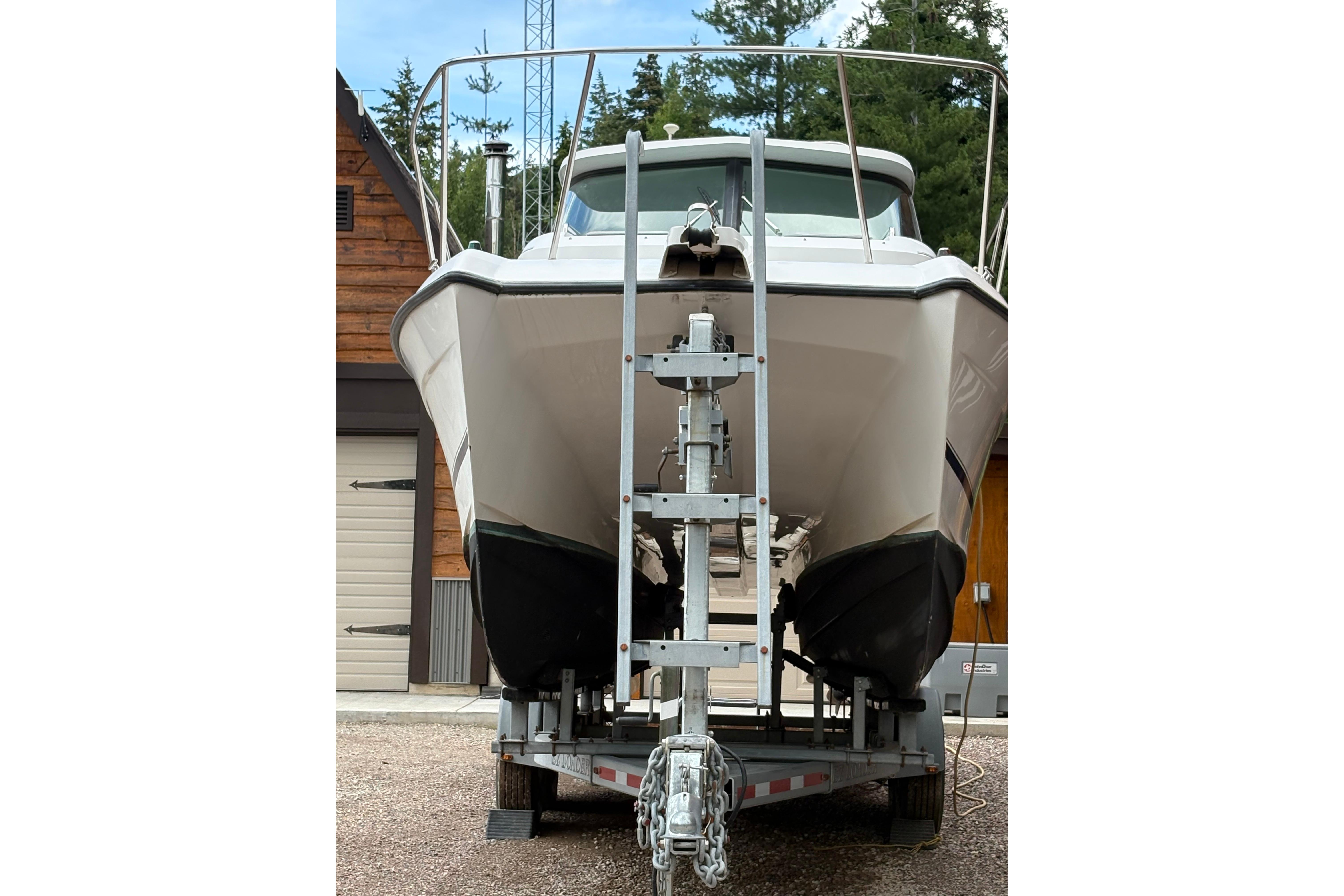 2001 Glacier Bay 2690 Coastal Runner boat on trailer, front view, near wooden building.