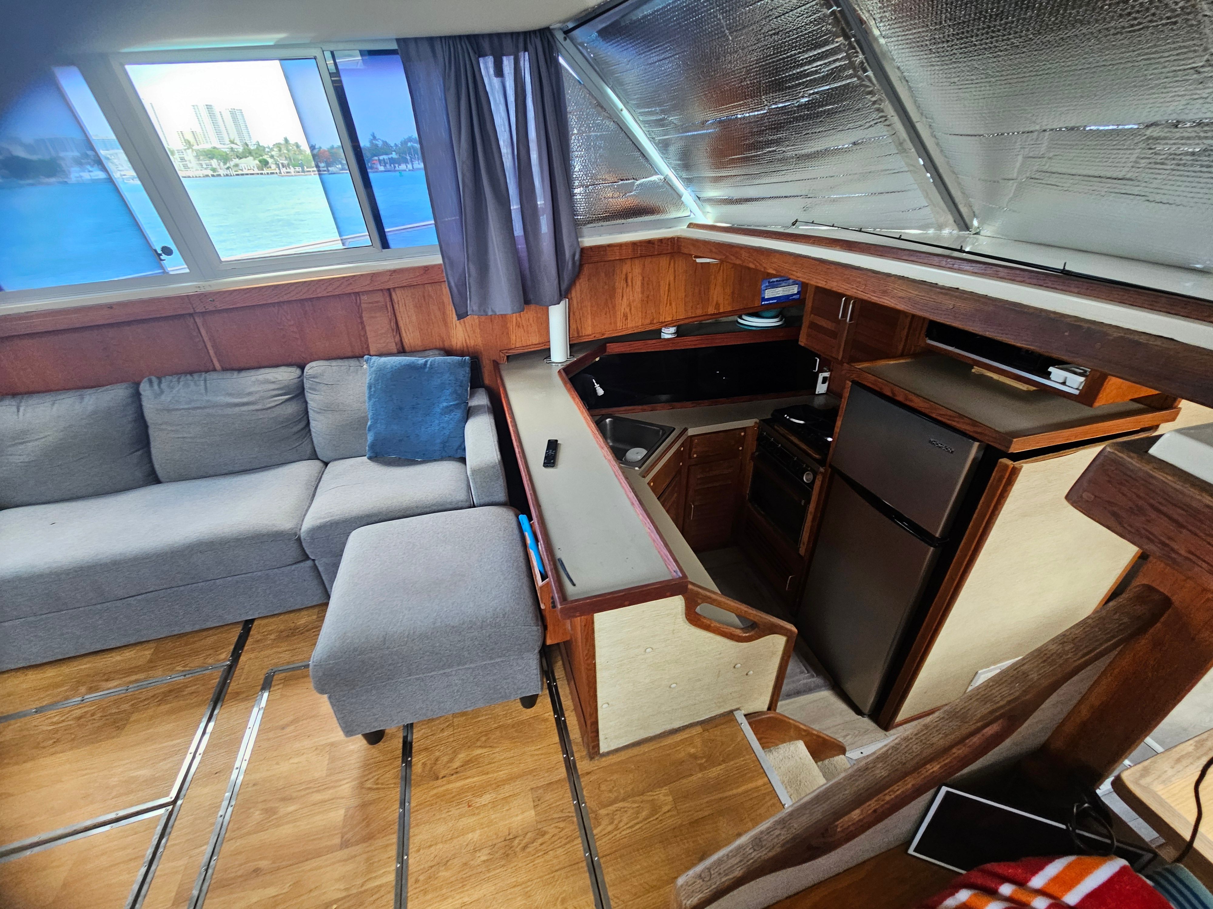 Interior of a 1984 Silverton 40 with a sofa, kitchen, and windows overlooking the water.