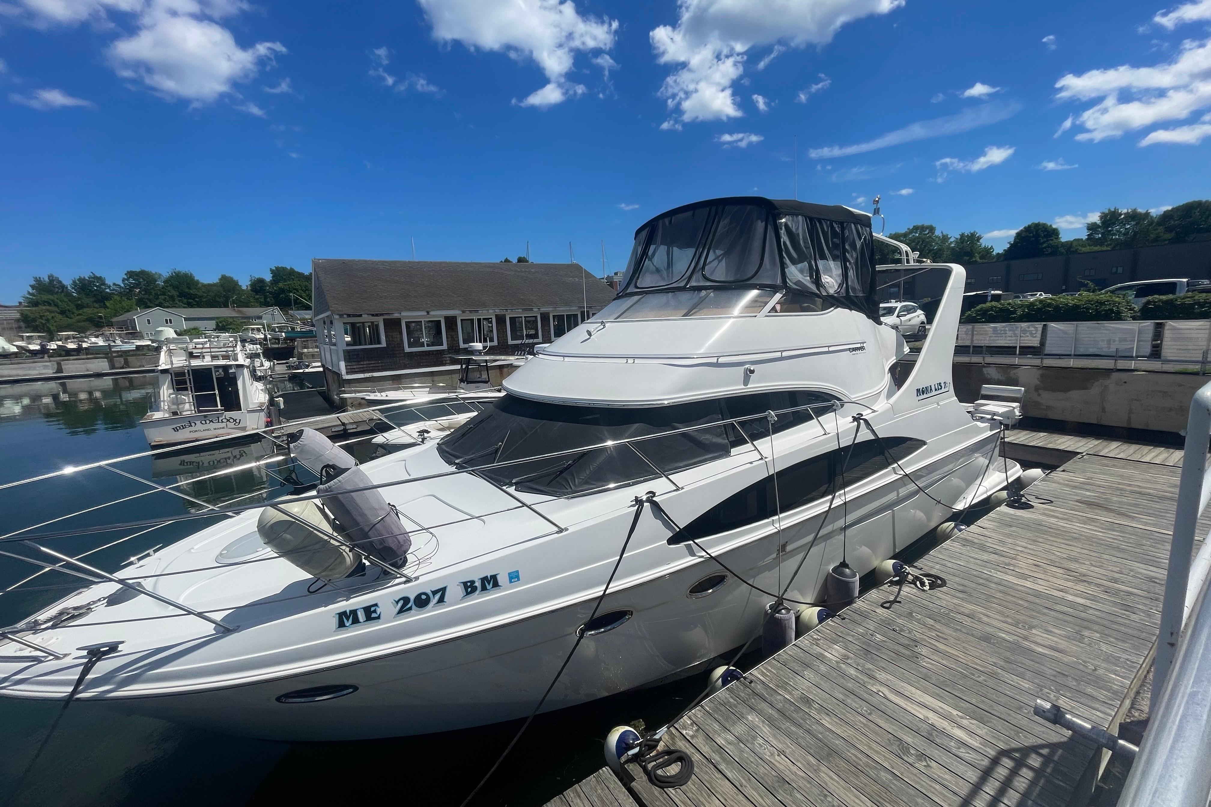 2002 Carver 410 Sport Sedan yacht docked at marina under blue sky.