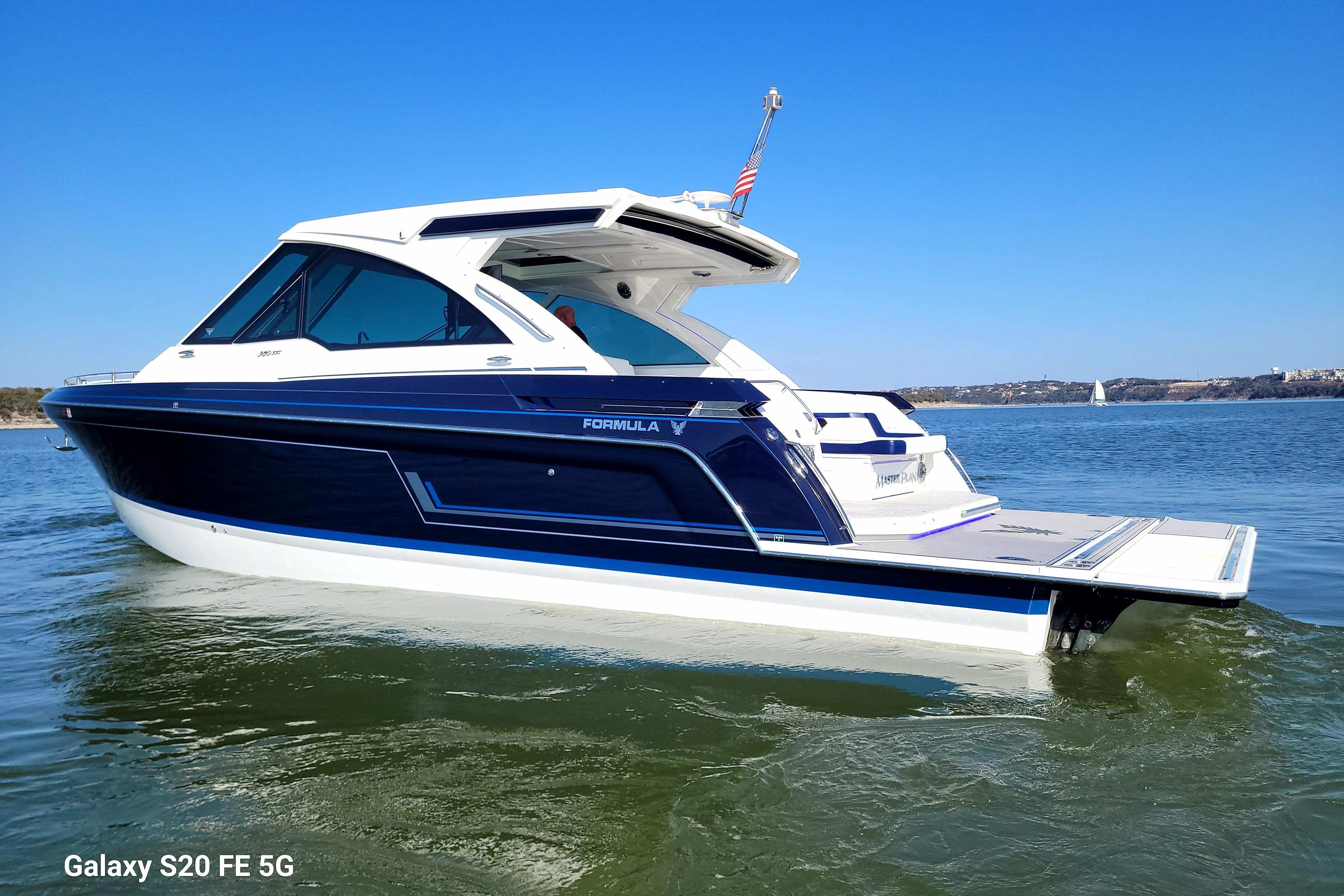 2023 Formula 380 Super Sport Crossover I/O boat on calm water, clear blue sky.