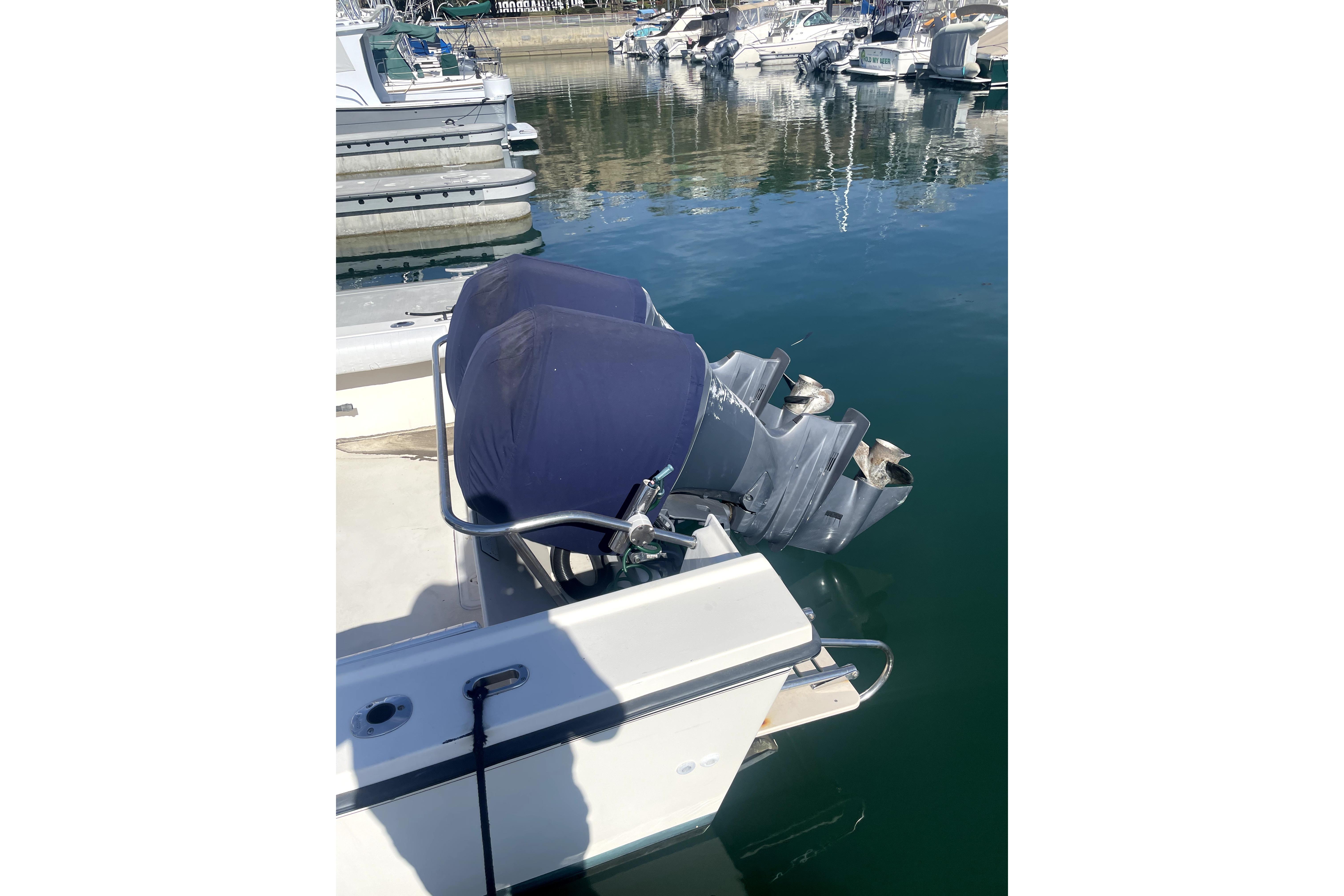 2006 Parker 2520 SL Sport Cabin boat with dual outboard motors at a marina.