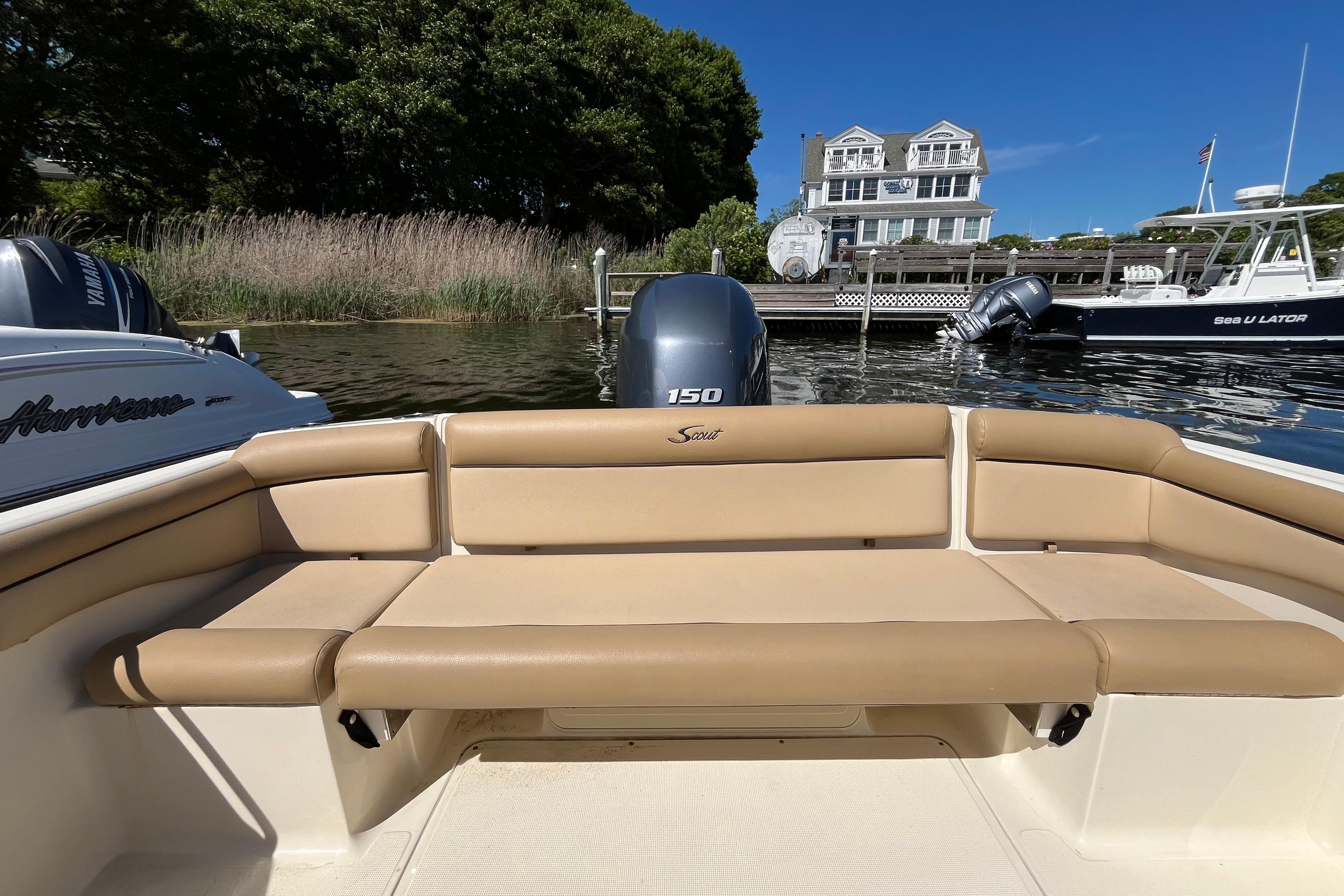 2017 Scout 210 Dorado boat with tan seating, docked near a waterfront house.