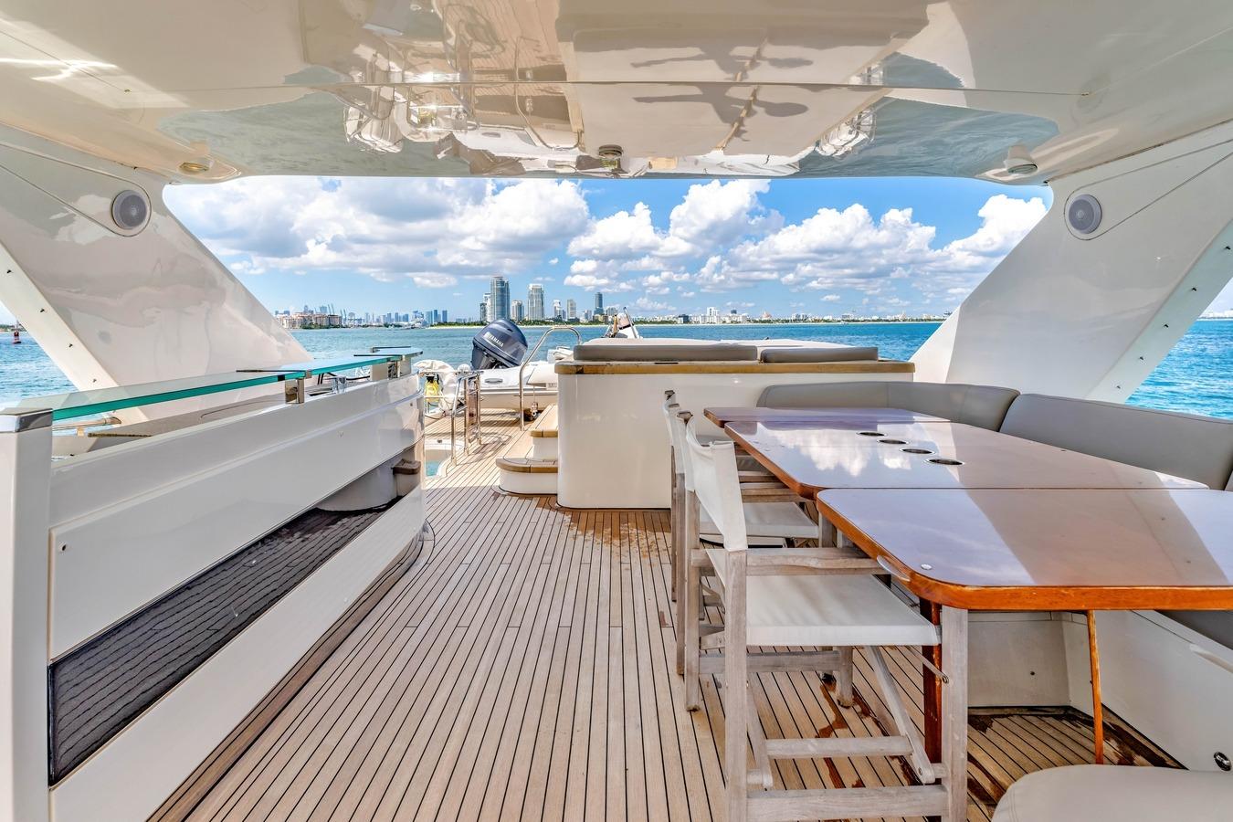 Luxurious 2012 Princess 85 yacht deck with dining area, overlooking ocean and city skyline.