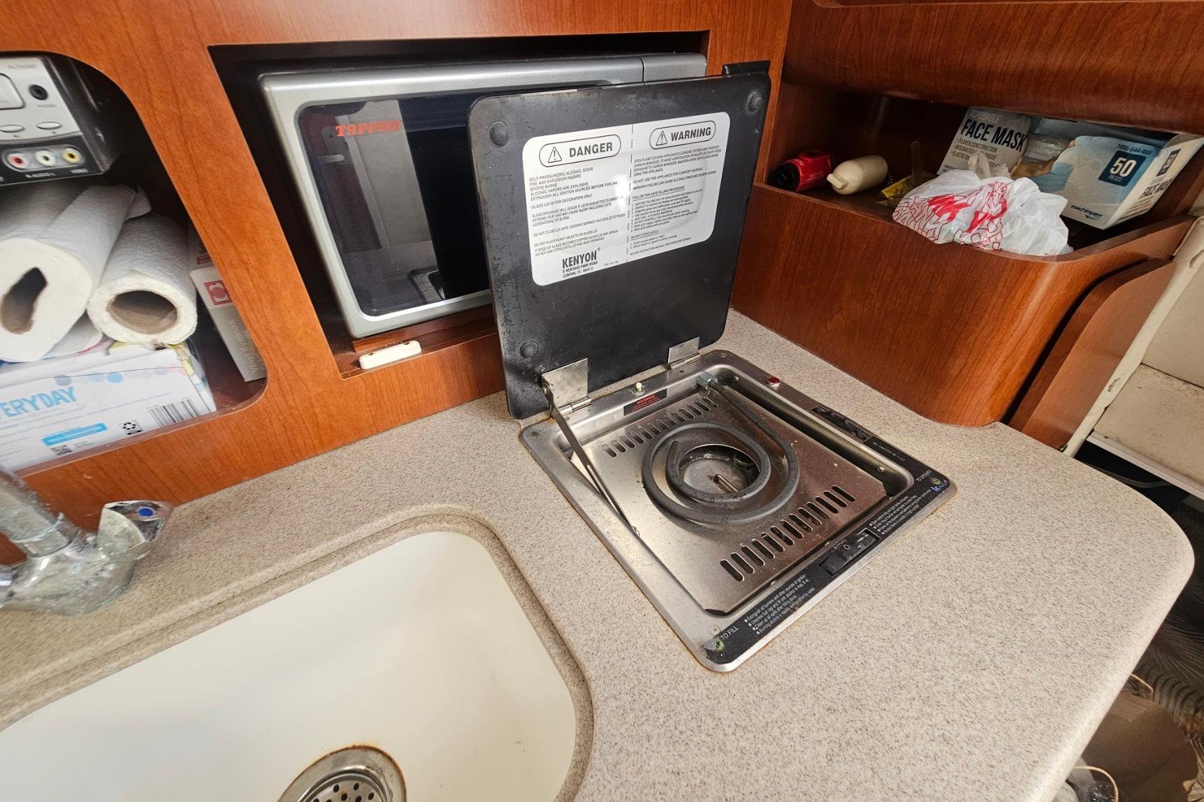 2006 Pro-Line 32 Express boat kitchen with stove, sink, and storage shelves.