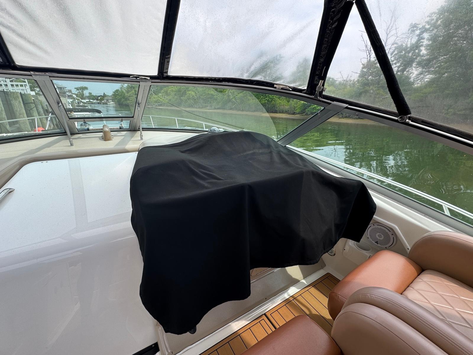 2003 Sea Ray 340 Sundancer cockpit with covered dashboard, leather seats, and scenic waterway view.
