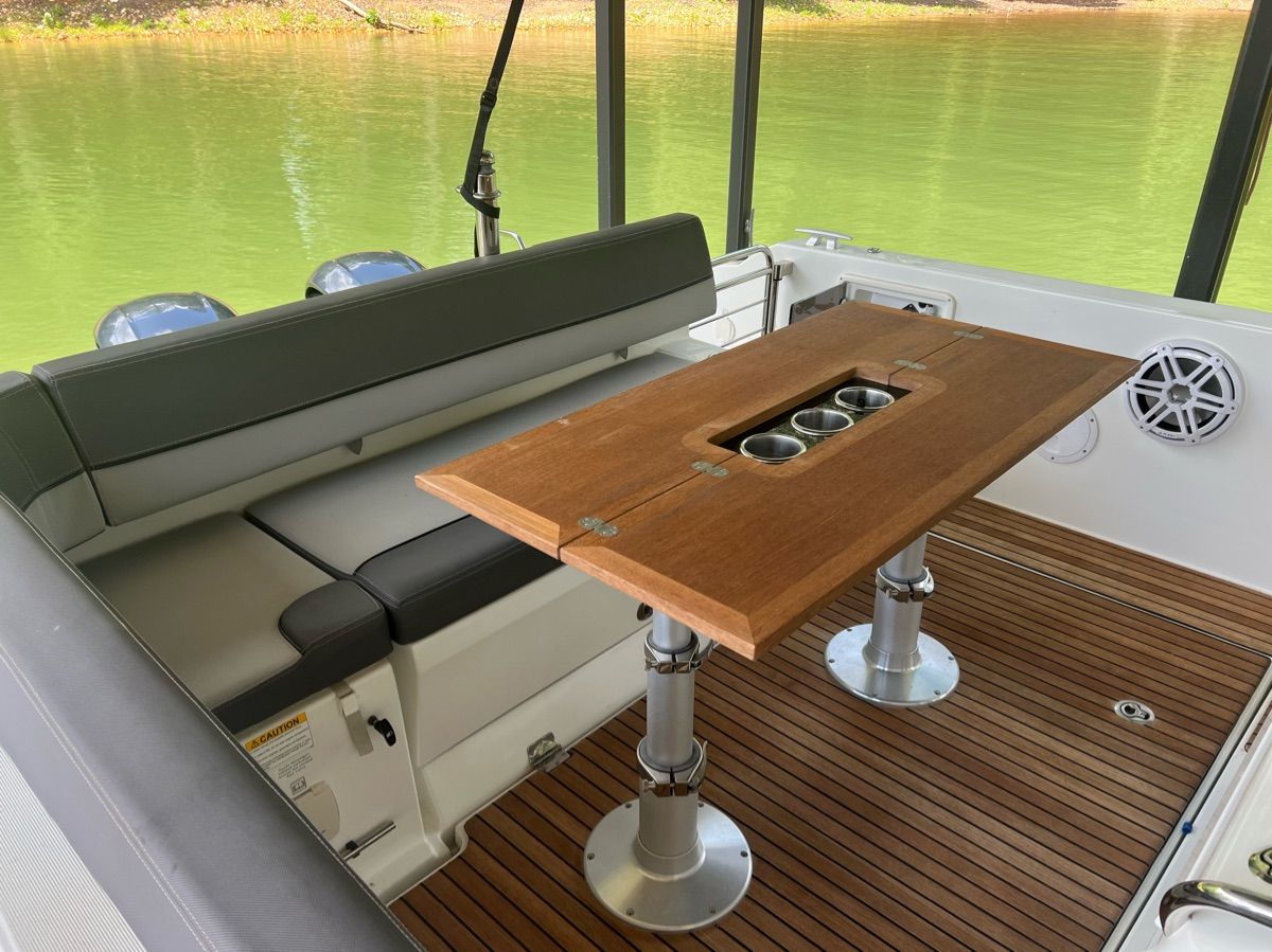 A sleek seating area with a wooden table and cup holders on a boat.