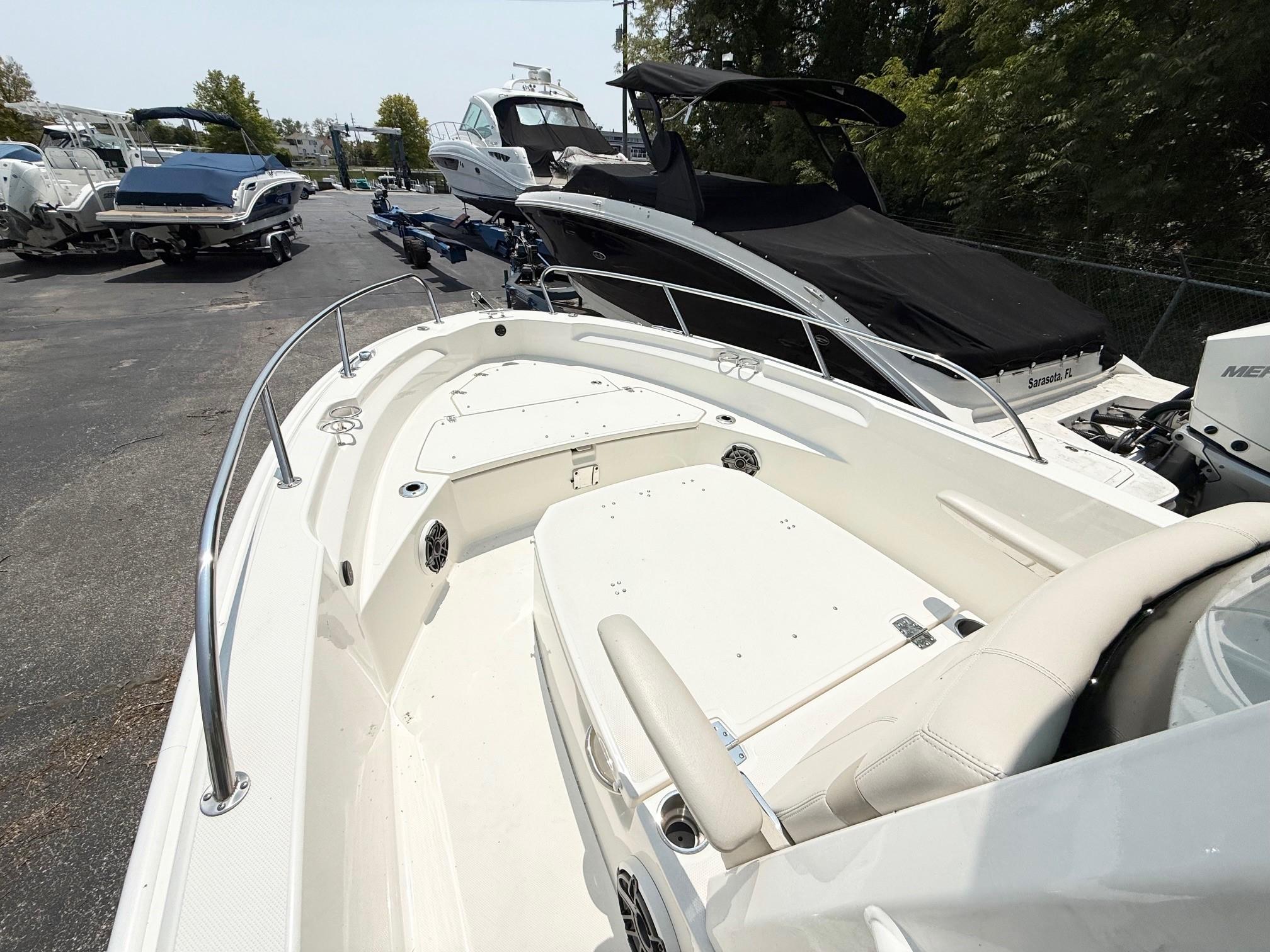 2022 Boston Whaler 220 Dauntless boat, white interior, docked among other boats.