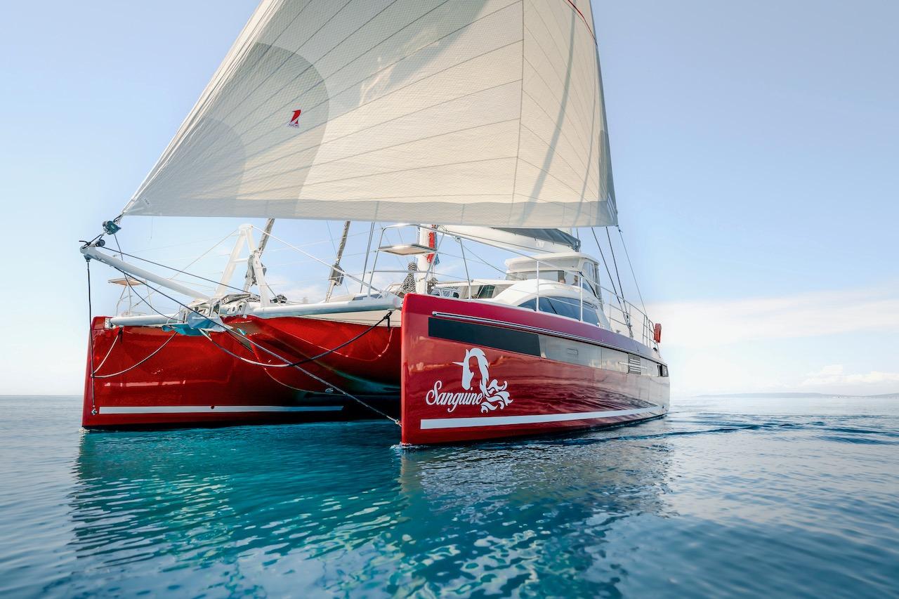 Red Privilege Signature 510 catamaran sailing on calm waters, year 2025.
