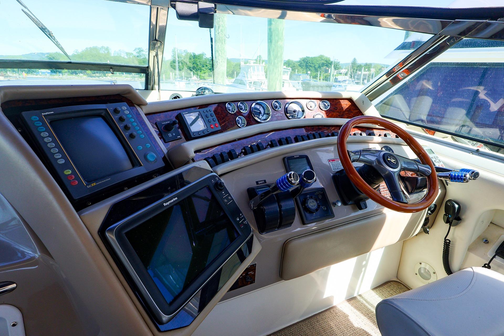 Cockpit of 1998 Sea Ray 500 Sundancer with navigation equipment and wooden steering wheel.